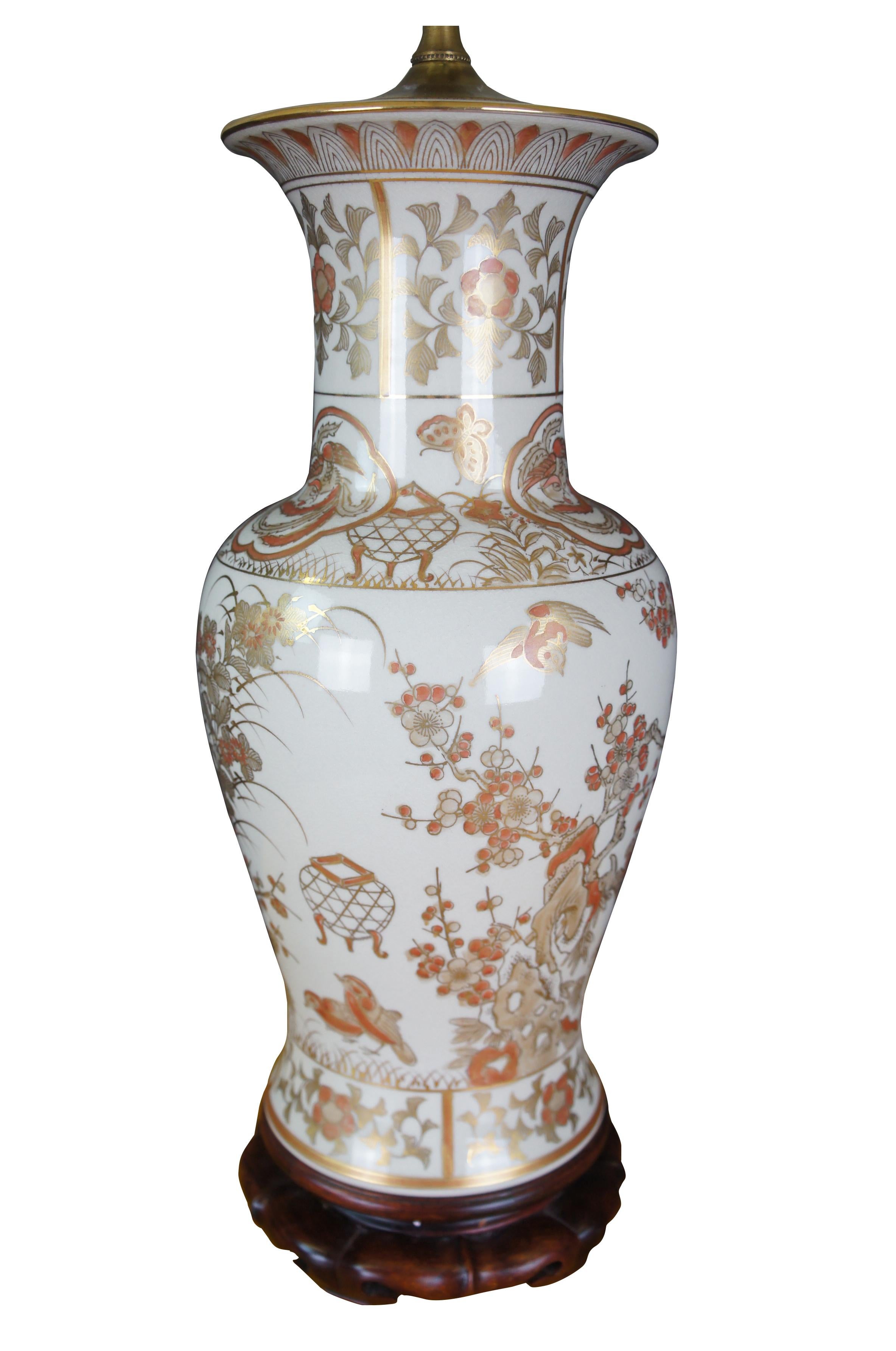 A Chinese porcelain table urn shaped table lamp. White with gold and orange colors. Features cherry blossoms and birds. The lamp is mounted to a wooden base. Features a jade finial and new shade. 

Measures: 7