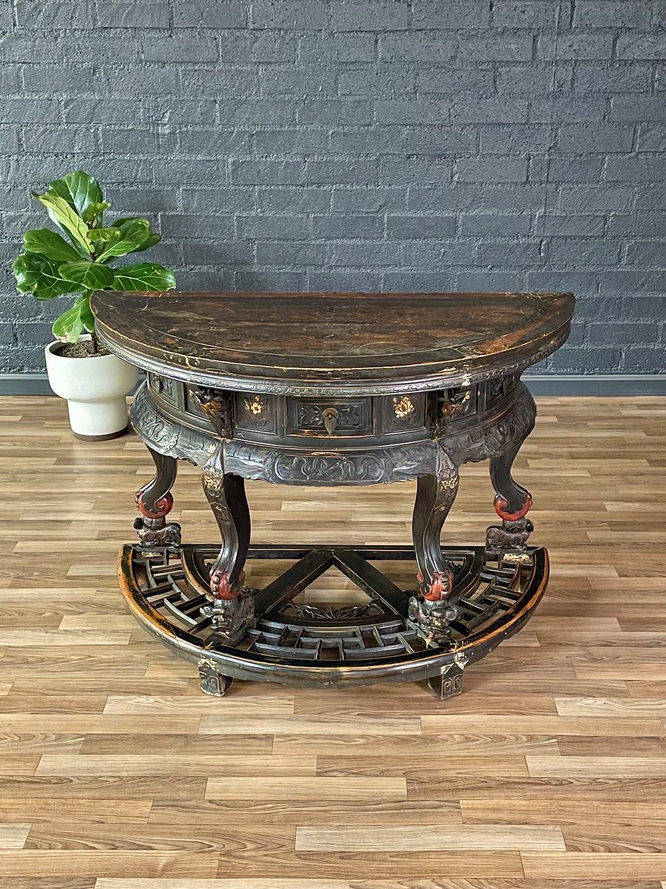 Cette table chinoise de la dynastie Qing, datant des années 1950, est le fruit d'un travail de maître, avec des détails minutieusement sculptés à la main et une riche finition ébonisée. La table présente les supports mythiques du chien Foo, qui