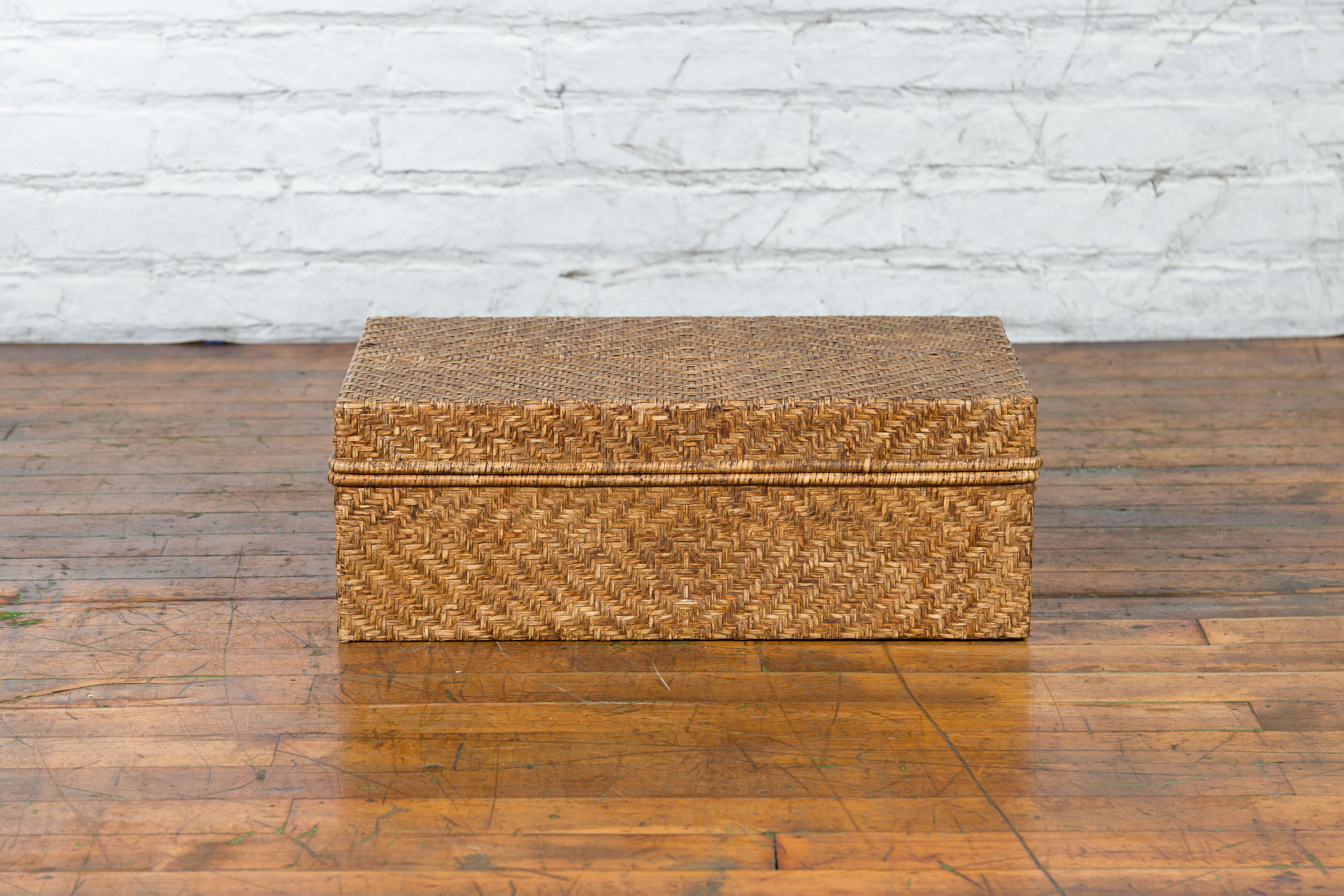 A vintage Chinese rattan box from the mid-20th century, great to be used as a low side table. Created in China during the mid-century period, this rattan box features a rectangular lid opening to reveal a convenient storage space. With its clean