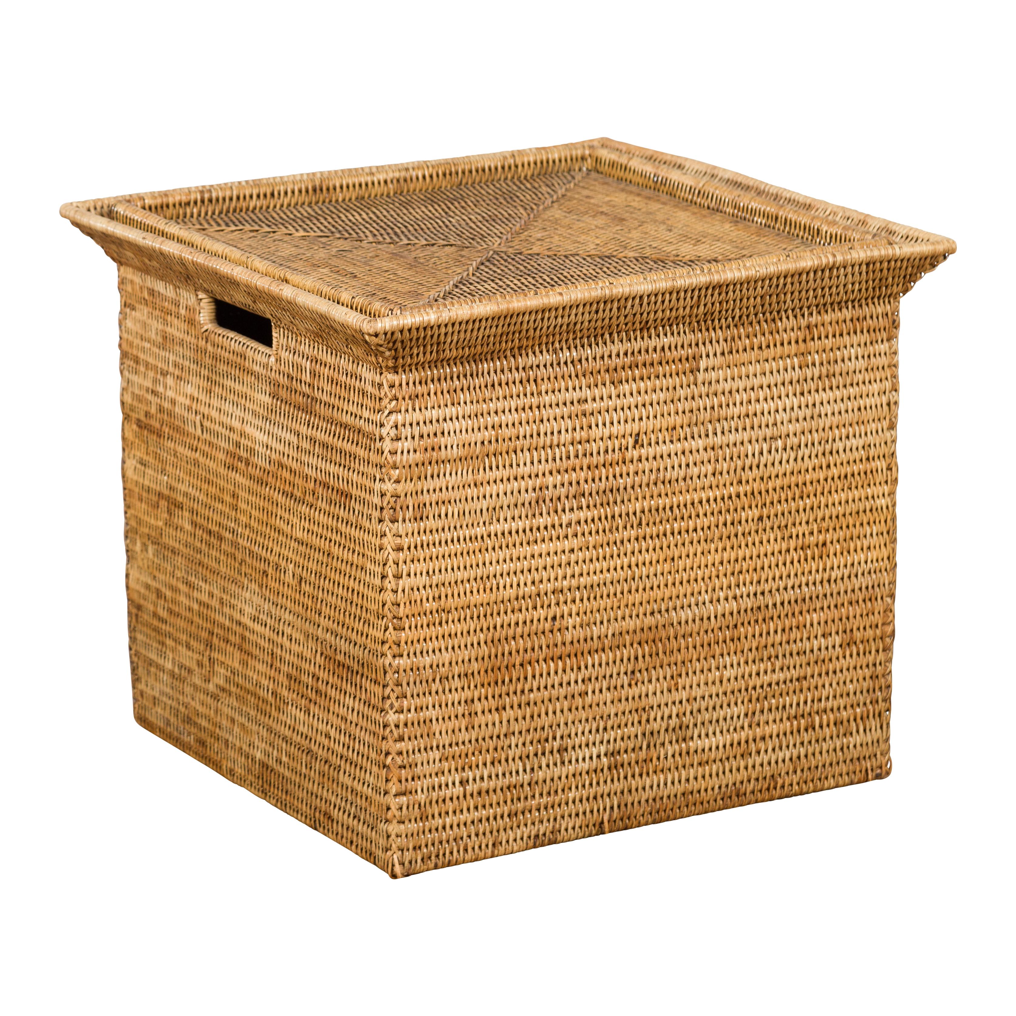 A vintage Chinese rattan storage box from the mid 20th century, with pierced handles. Created in China during the midcentury period, this rattan box features a beveled top securing a square lid with triangular patterns. Pierced with handles on two