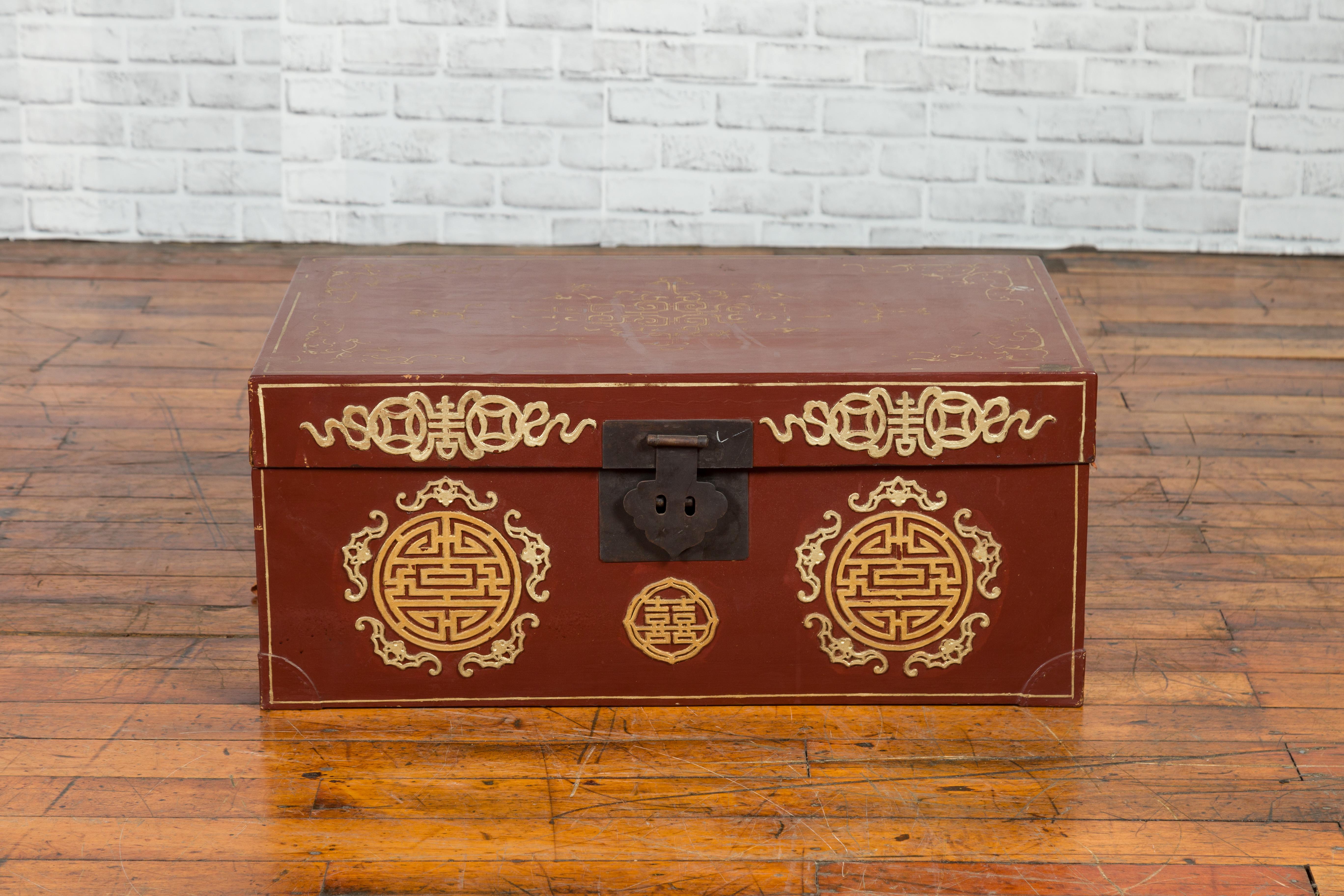 A vintage Chinese red blanket chest from the 20th century, with gold details and calligraphy motifs. Created in China during the 20th century, this blanket chest features a linear silhouette perfectly complimented by red and golden tones. Adorned