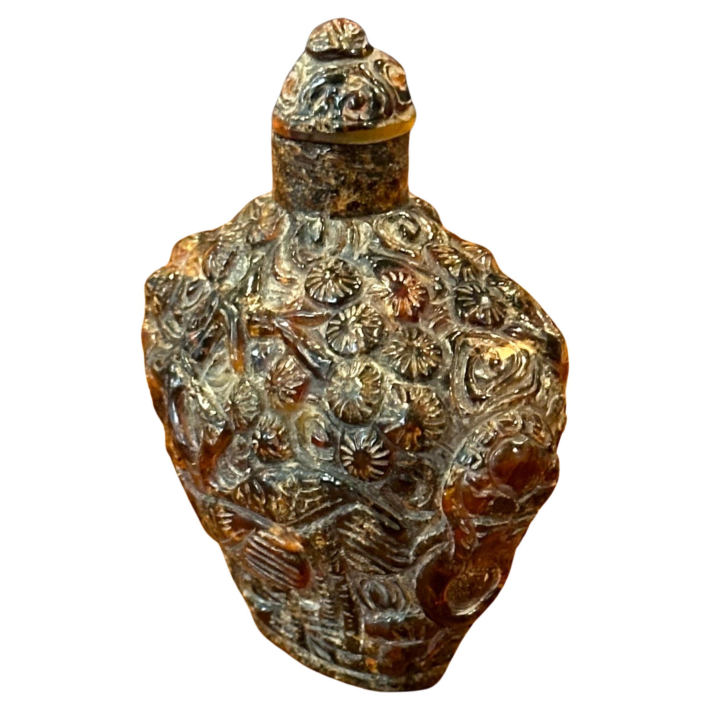 A vintage Chinese relief amber snuff bottle, circa 1970s.   Amber is fossilized tree resin that has been appreciated for its color and natural beauty since Neolithic times. Much valued from antiquity to the present as a gemstone, amber is made into