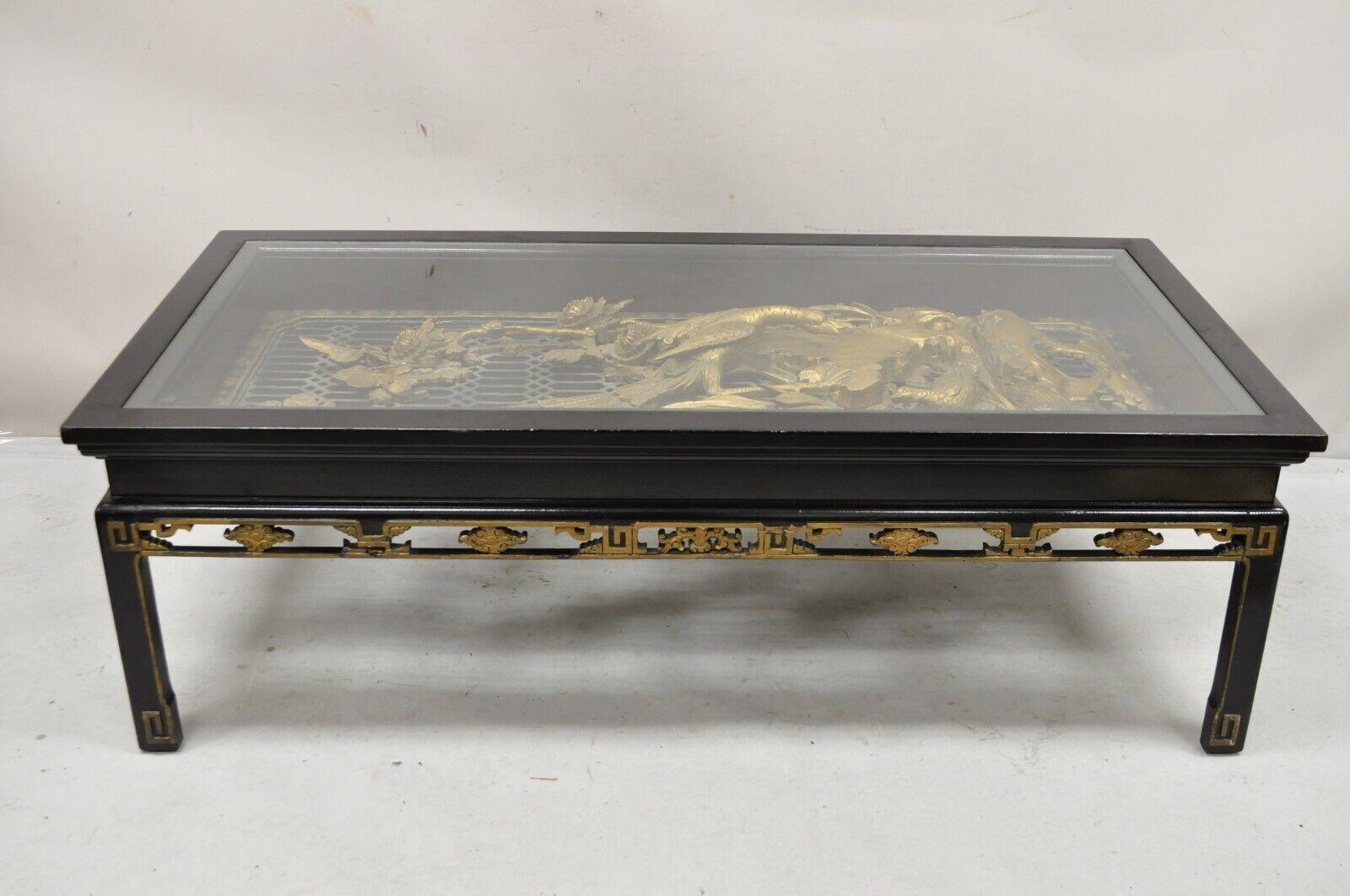 Vintage Chinese Relief Carved Ho ho Bird Glass Top Display Black Coffee Table. Item features a solid wood frame, black and gold painted finish, finely relief carved flower, butterfly, and ho ho bird display, very nice vintage item. Circa Mid 20th