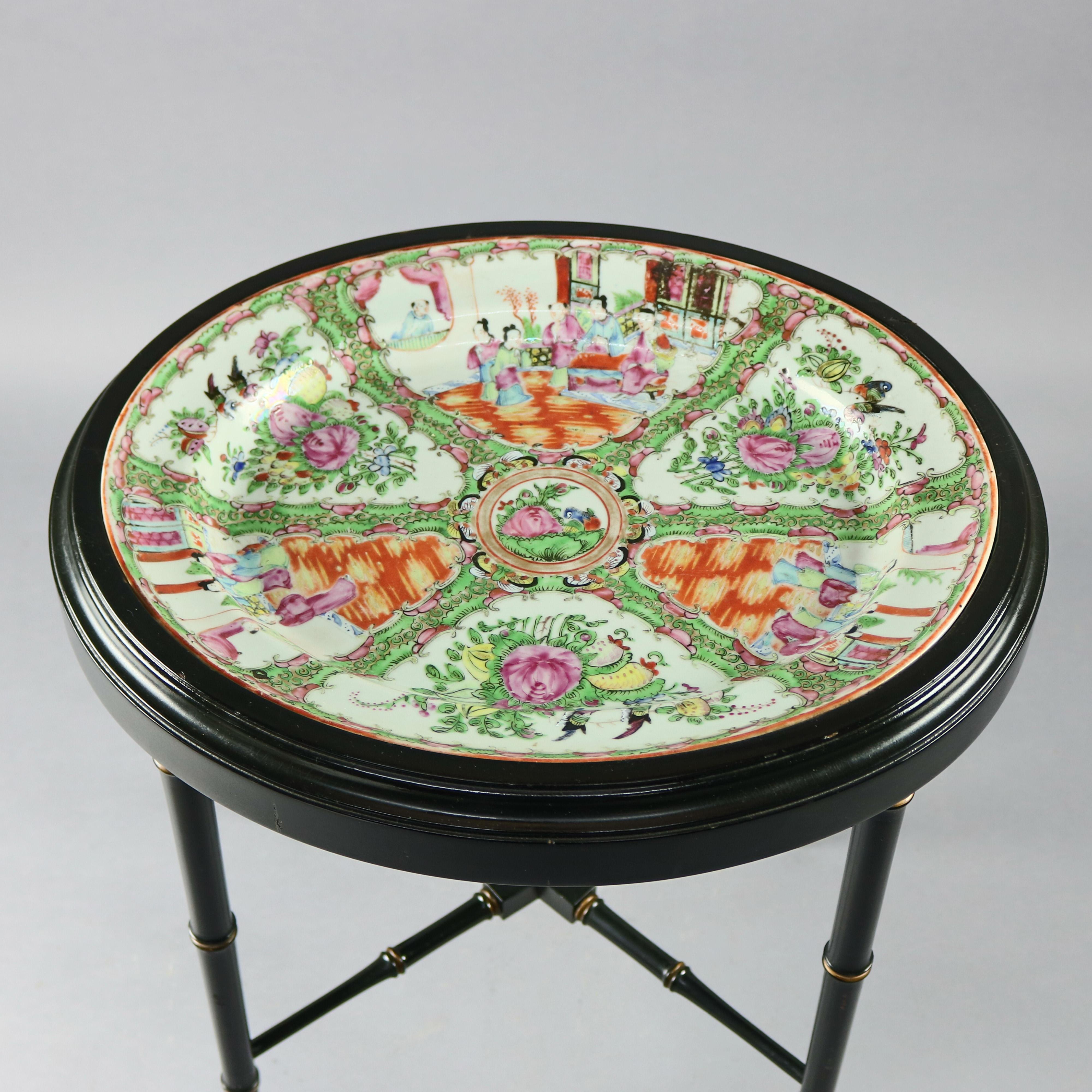 Vintage Chinese tea table offers removable hand enameled porcelain tray with reserves having garden and interior scenes with figures seated in ebonized stand with bamboo form legs and gilt highlights, circa 1940

Measures - 18.75