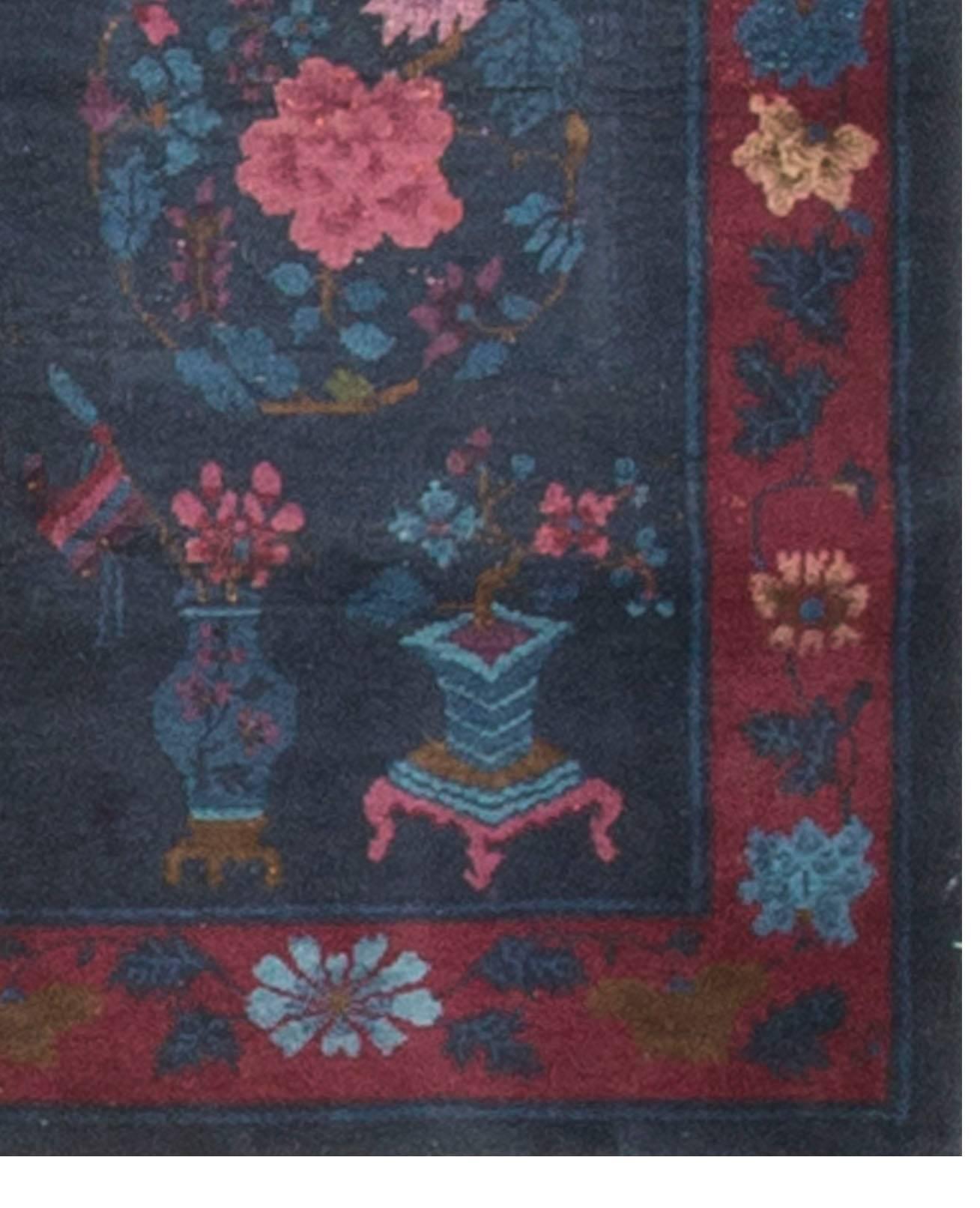 An unusual design in this 1950s Chinese rug. The two urns holding flowers are repeated in mirror image at both ends of the rug with a circular globe pattern in the center with beautiful floral designs. The main border surrounded by the blues in the