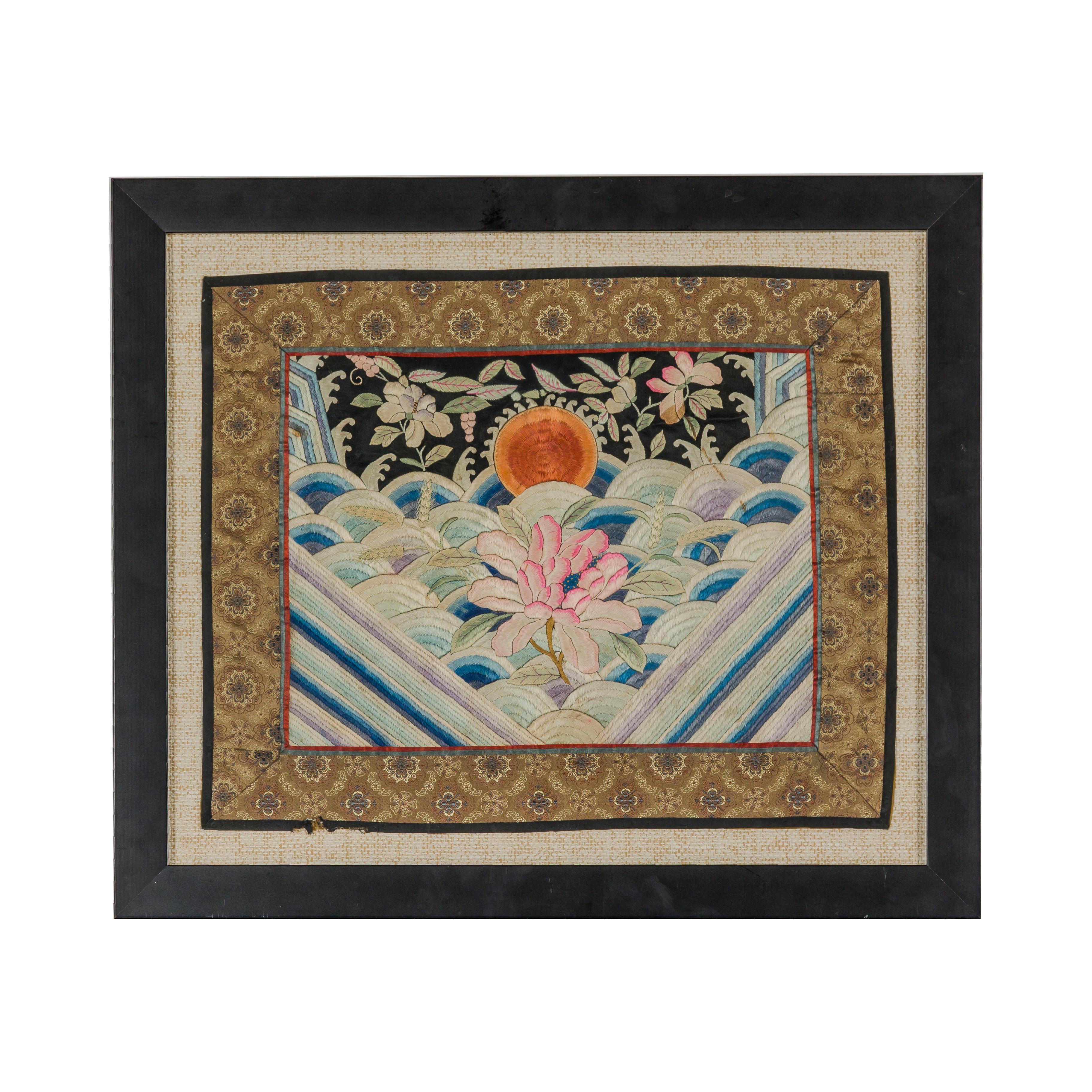 A vintage Chinese silk fabric depicting pink flowers, waves and the sun set in a black custom made frame, under glass. This vintage Chinese silk fabric, elegantly framed under glass, is a piece steeped in history and beauty. Once perhaps a segment