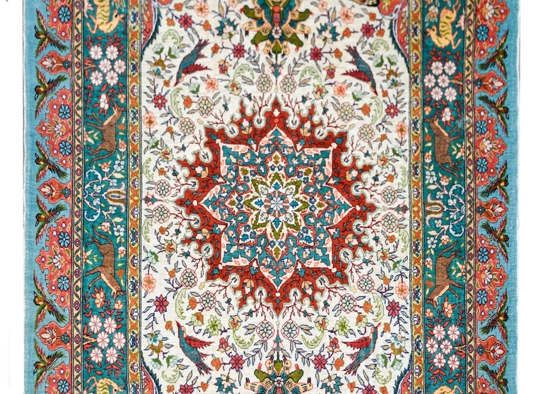 A beautiful vintage Chinese hand-knotted silk rug with a large central medallion resting on a field of scrolling vines, flowers, and birds, all woven in crimson, indigo, orange, gold, and green set against a white background. The border is wonderful