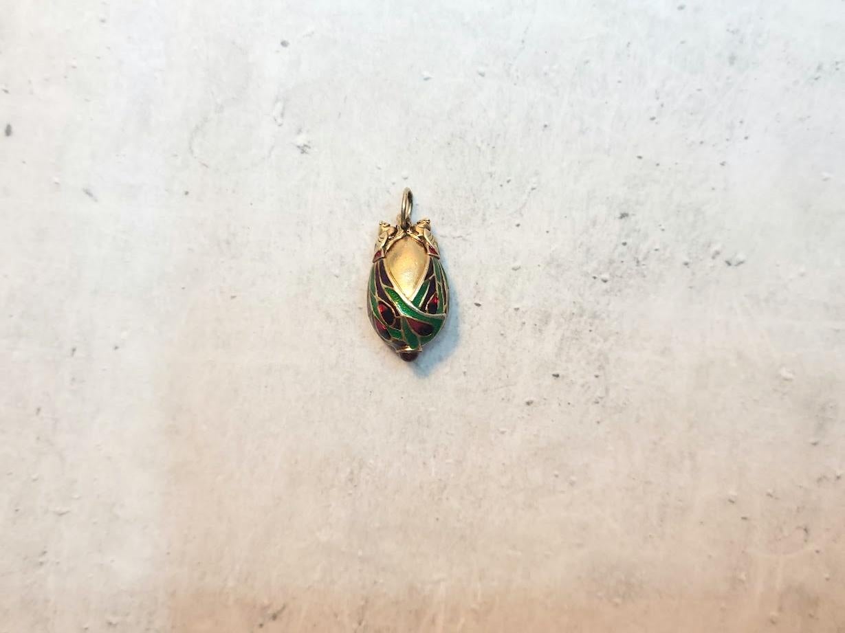 This exquisite vintage Chinese gilded silver egg pendant, adorned with stunning enamel and granulated accents, features the revered two birds peacocks. The bottom of the egg is decorated with a tiny garnet (rhodolite) cabochon. In China, the peacock