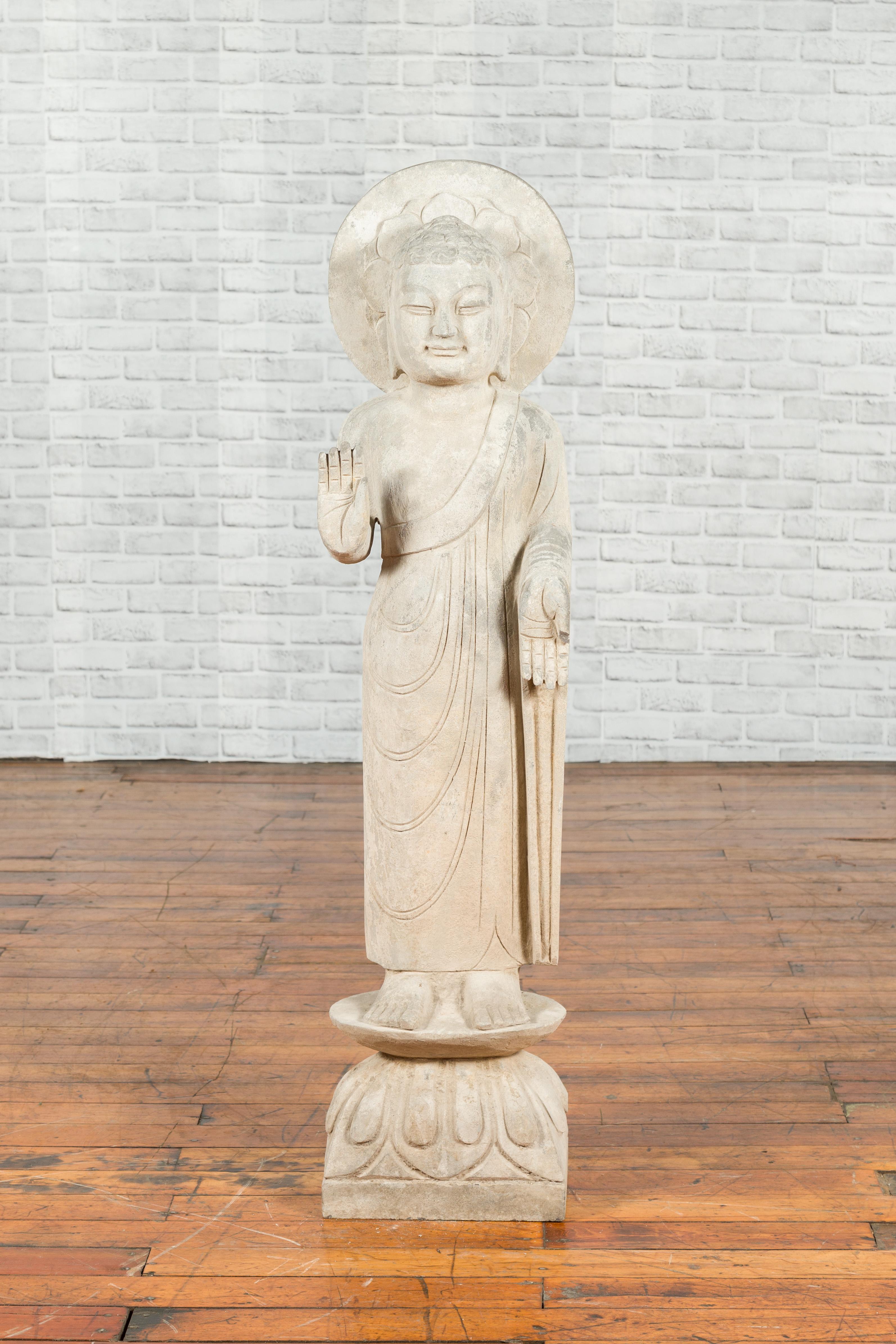 A vintage Chinese carved stone standing Buddha with Abhayamudra from the mid-20th century. Created in China during the midcentury period, this standing Buddha features the Abhaya mudra, the gesture of fearlessness. This mudra represents protection,