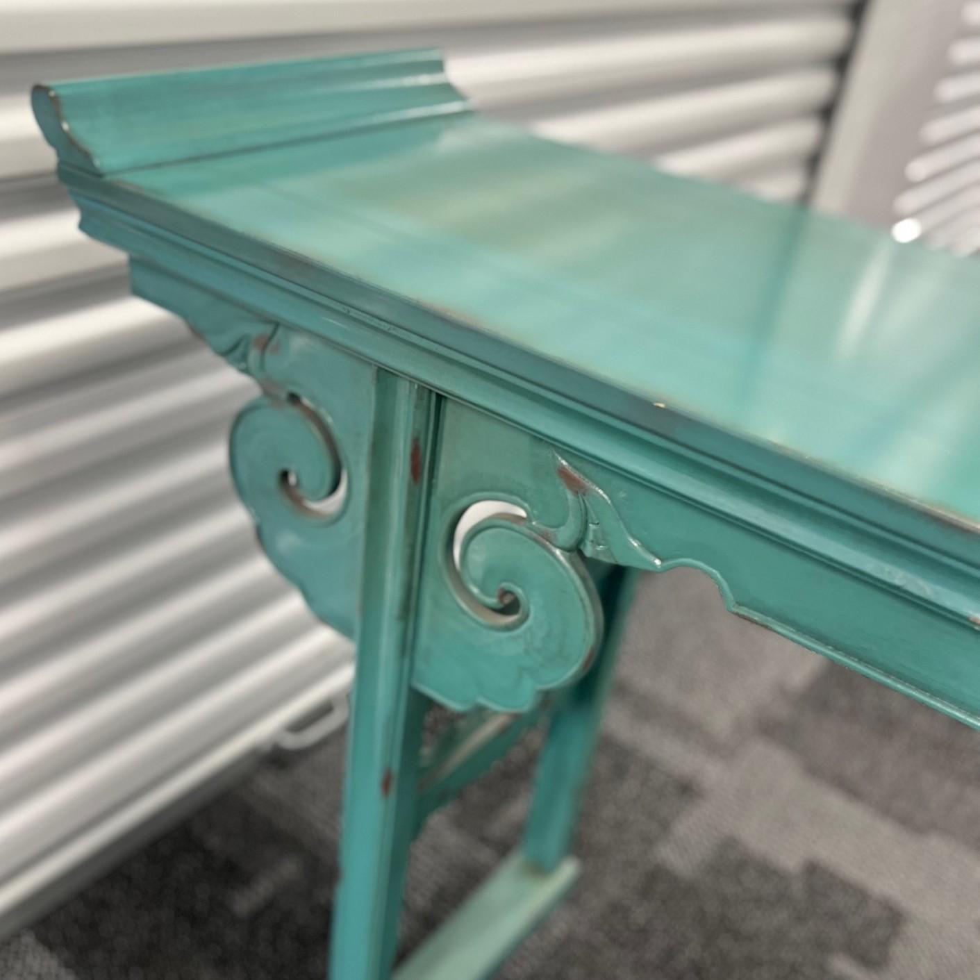 Vintage Chinese-style altar console table, finished in a striking distressed turquoise lacquer. This piece features carved scroll motifs along the legs and aprons, reflecting traditional Ming and Qing Dynasty influences. The table’s long, narrow