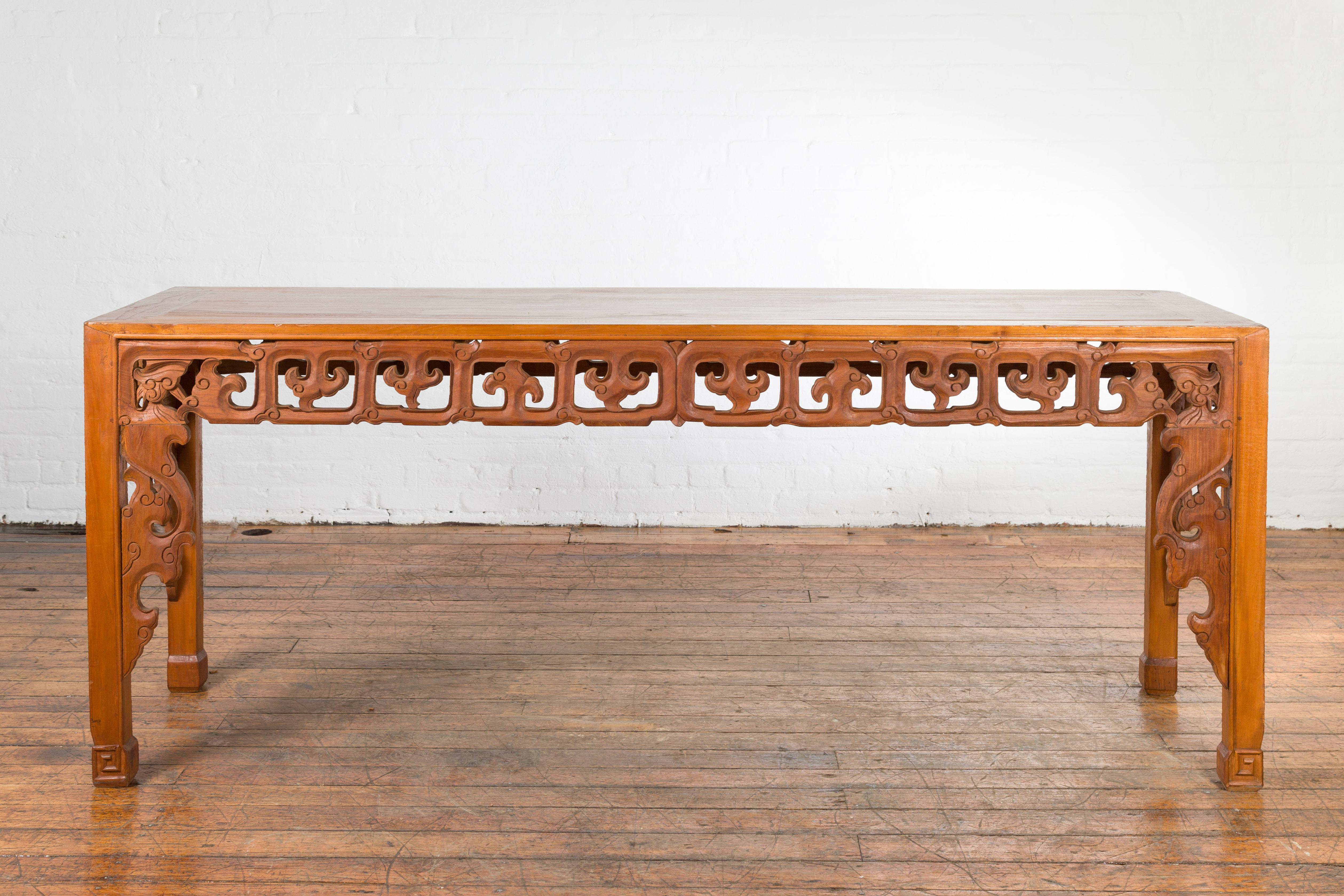 An Indonesian Chinese style vintage teak wood altar table from the mid 20th century with carved motifs. Found in Madura, Indonesia, this console table features a rectangular top with central board, sitting above a beautifully carved apron adorned