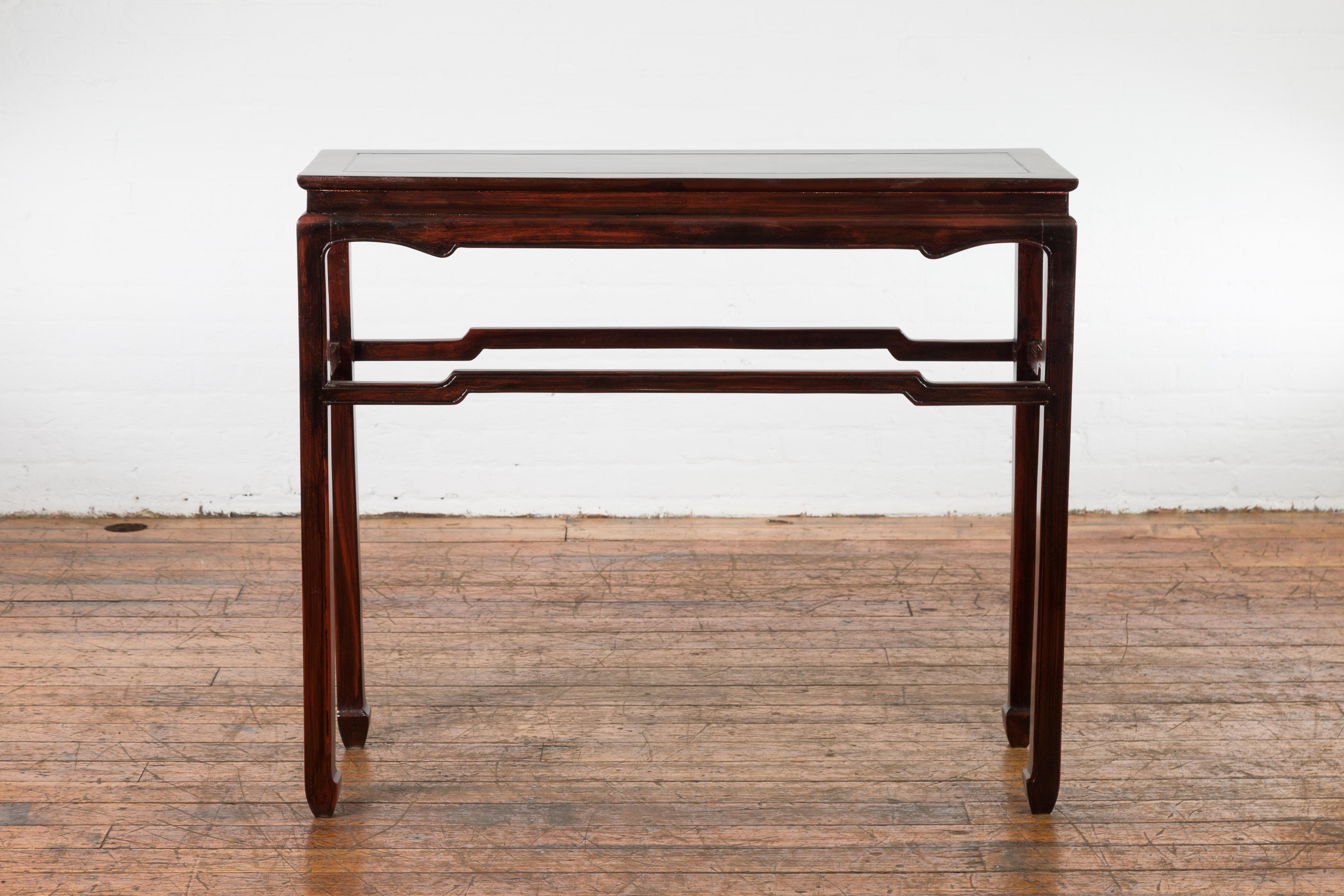 A vintage Chinese style Thai wine console table from the Mid-20th Century, with reddish brown new custom lacquer, waisted top, carved apron, hump back stretchers and horse hoof legs. Created in Thailand during the midcentury period, this wooden