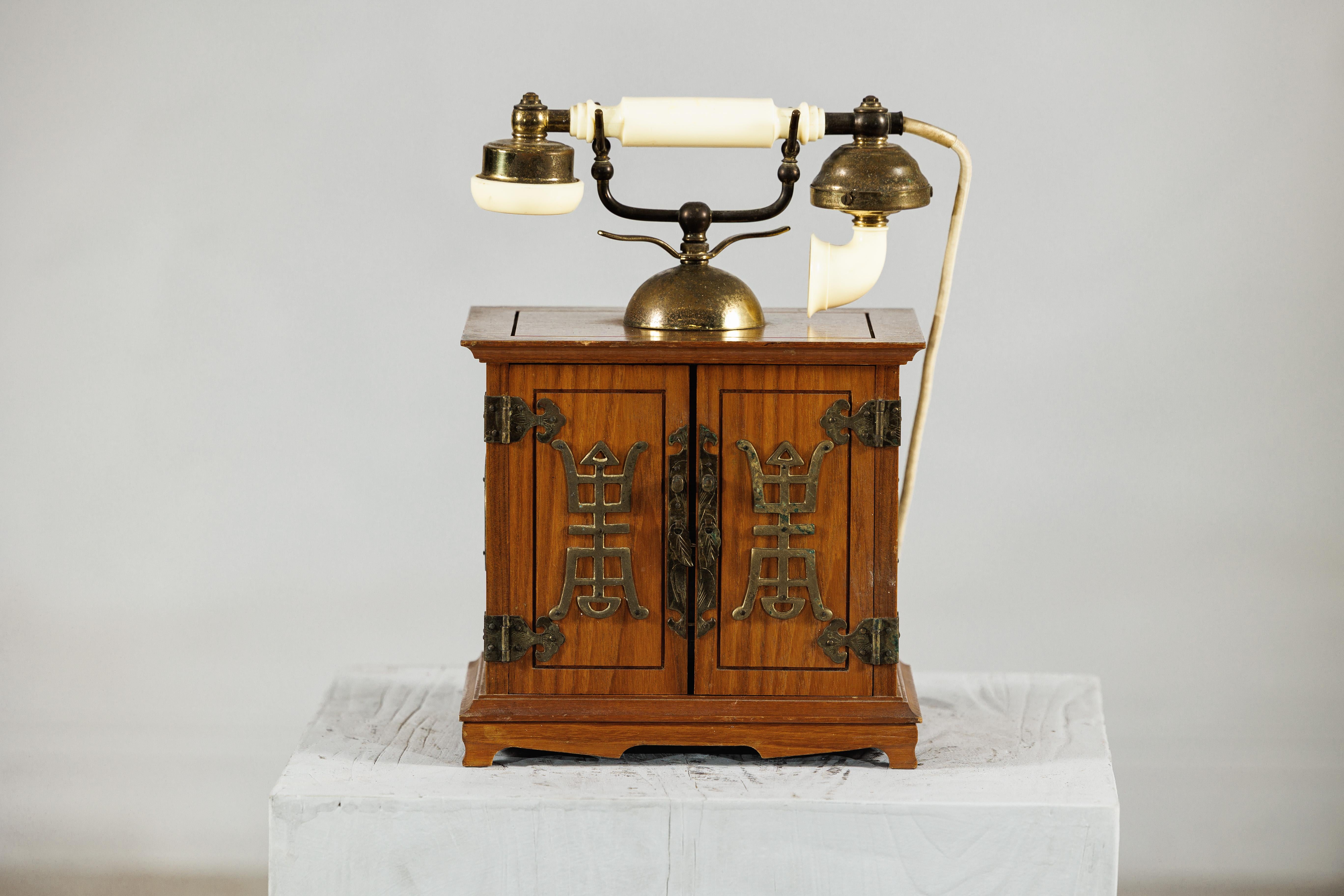 Questo telefono cinese vintage combina l'eleganza di ispirazione francese con il fascino dell'artigianato di metà secolo. La cornetta, con i suoi campanelli in ottone e gli accenti color avorio, ricorda le classiche silhouette dei primi telefoni