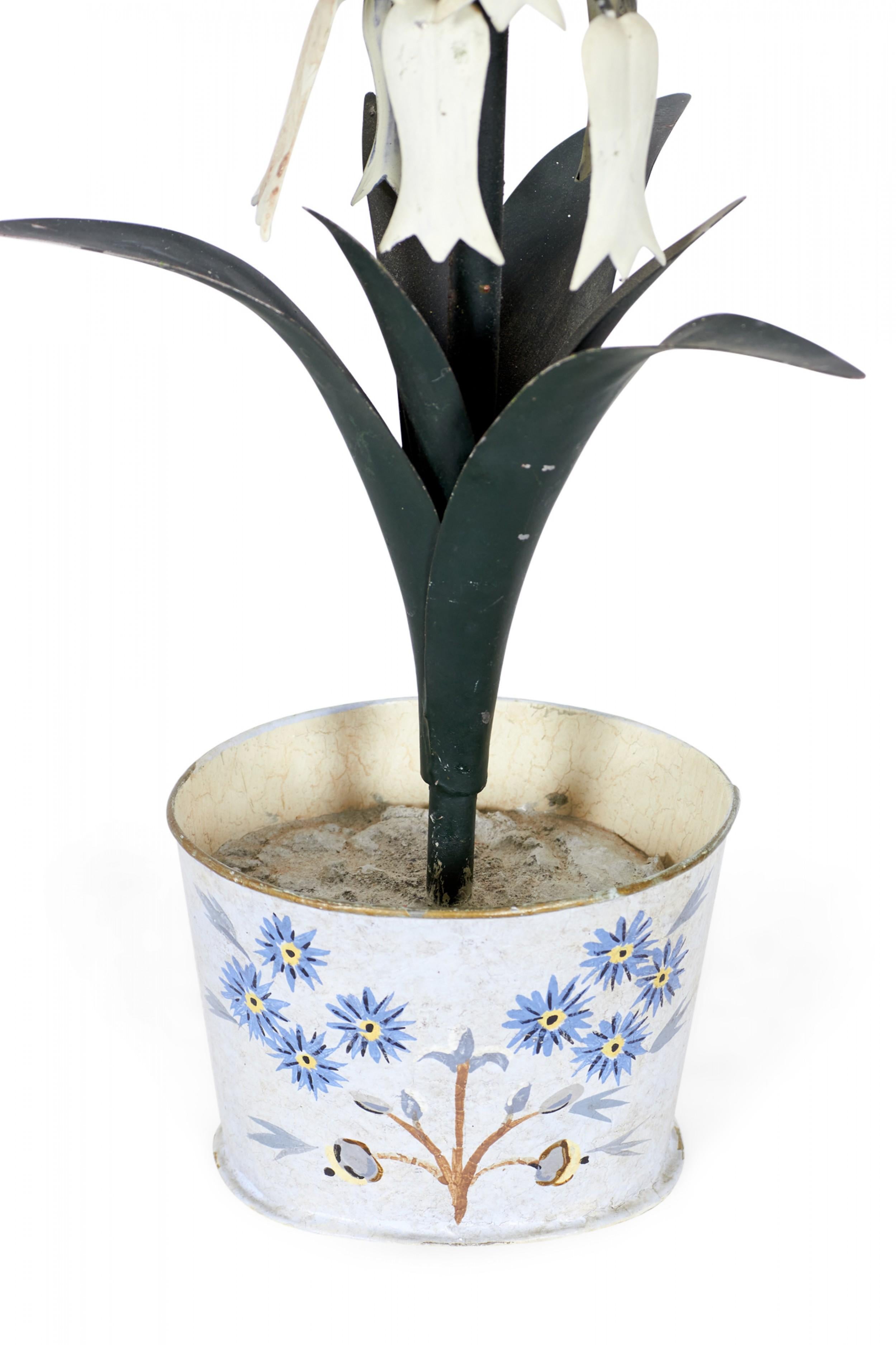 Vintage Chinese tole and iron decorative potted flower sculpture with white flowers connected to a green multi-leaf stalk, mounted in a circular white and blue metal base pot. (Similar sculpture with different pot: NWL2725)