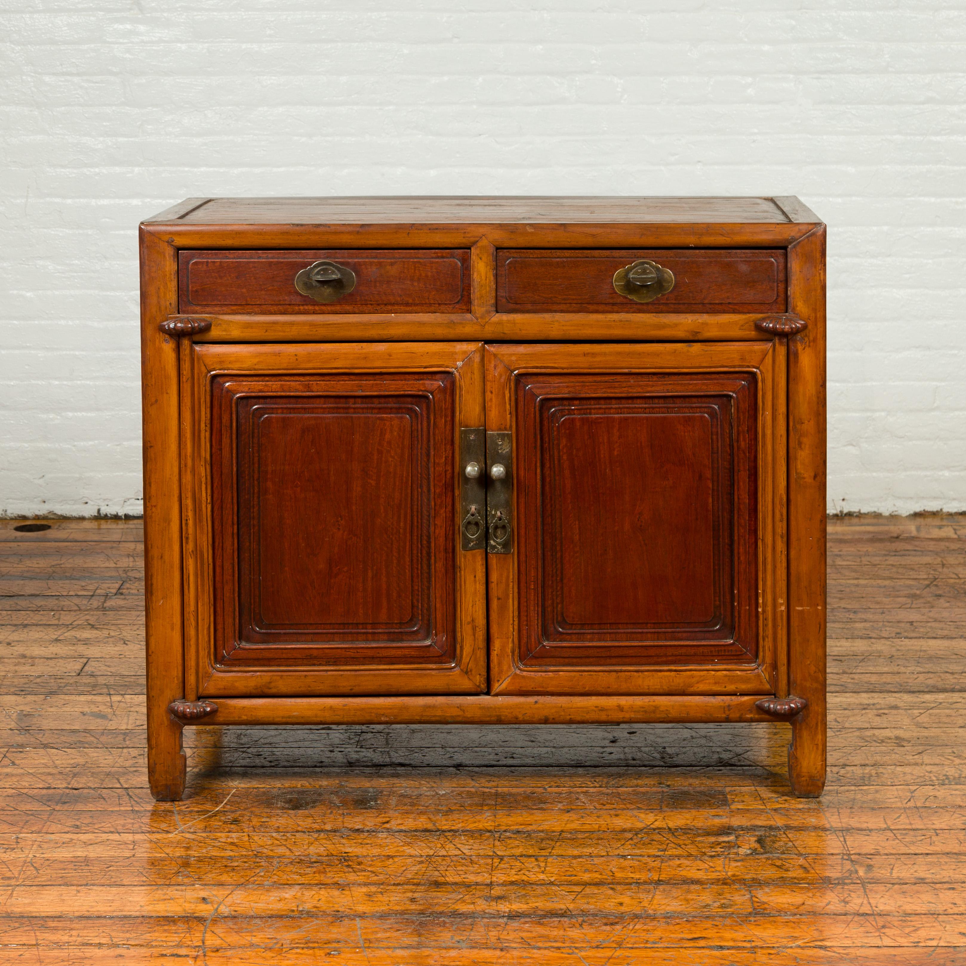 A Chinese vintage two-toned cabinet from the mid-20th century, with two drawers over two doors. Created in China during the midcentury period, this vintage cabinet features a rectangular top with central board, sitting above two drawers fitted with