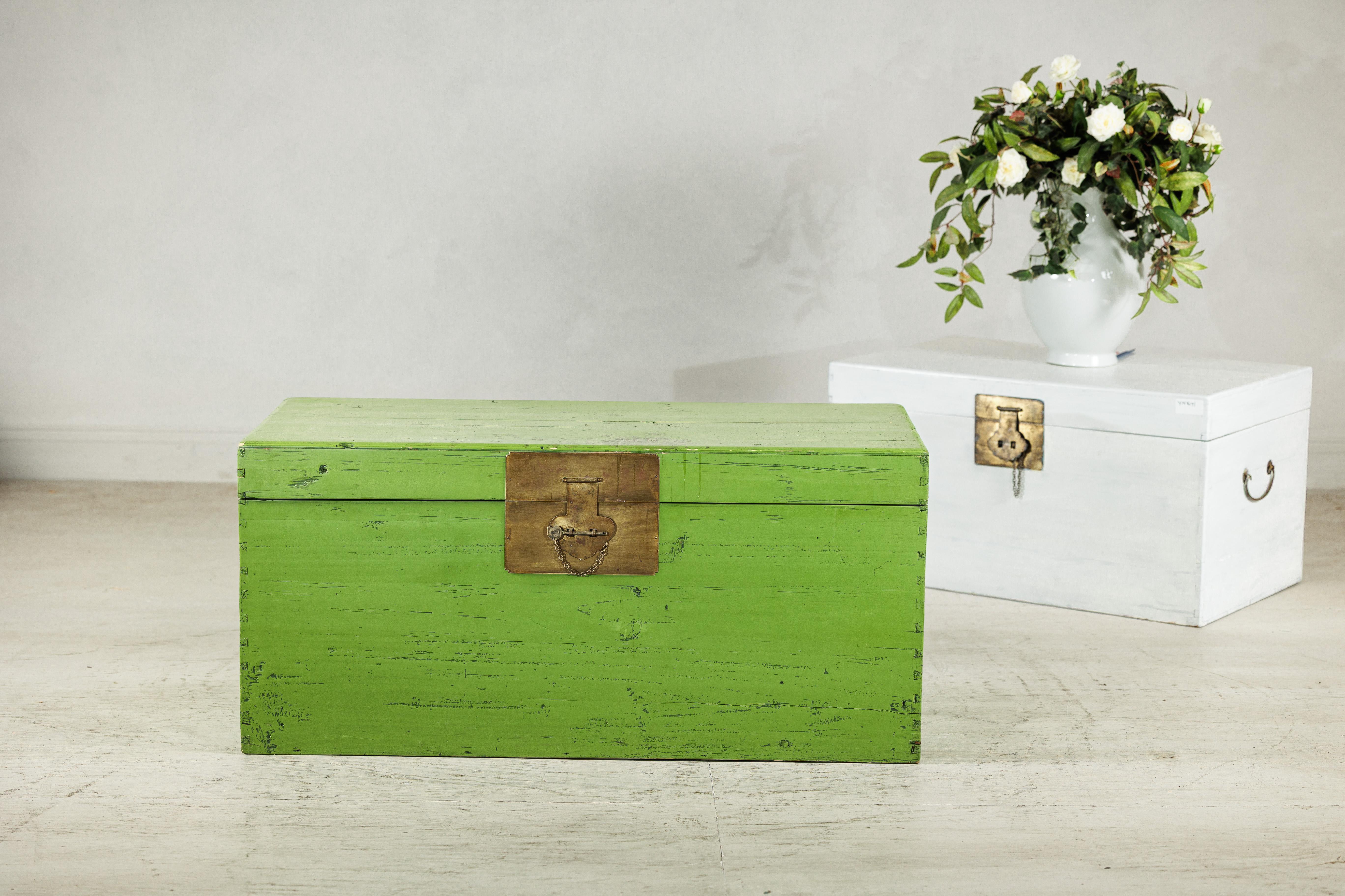 This vintage Chinese trunk captures attention with its vibrant green painted finish, softened by areas of natural wear that reveal its age and hand-crafted origins. Rectangular in form, the trunk is fitted with a brass lock plate and chain,