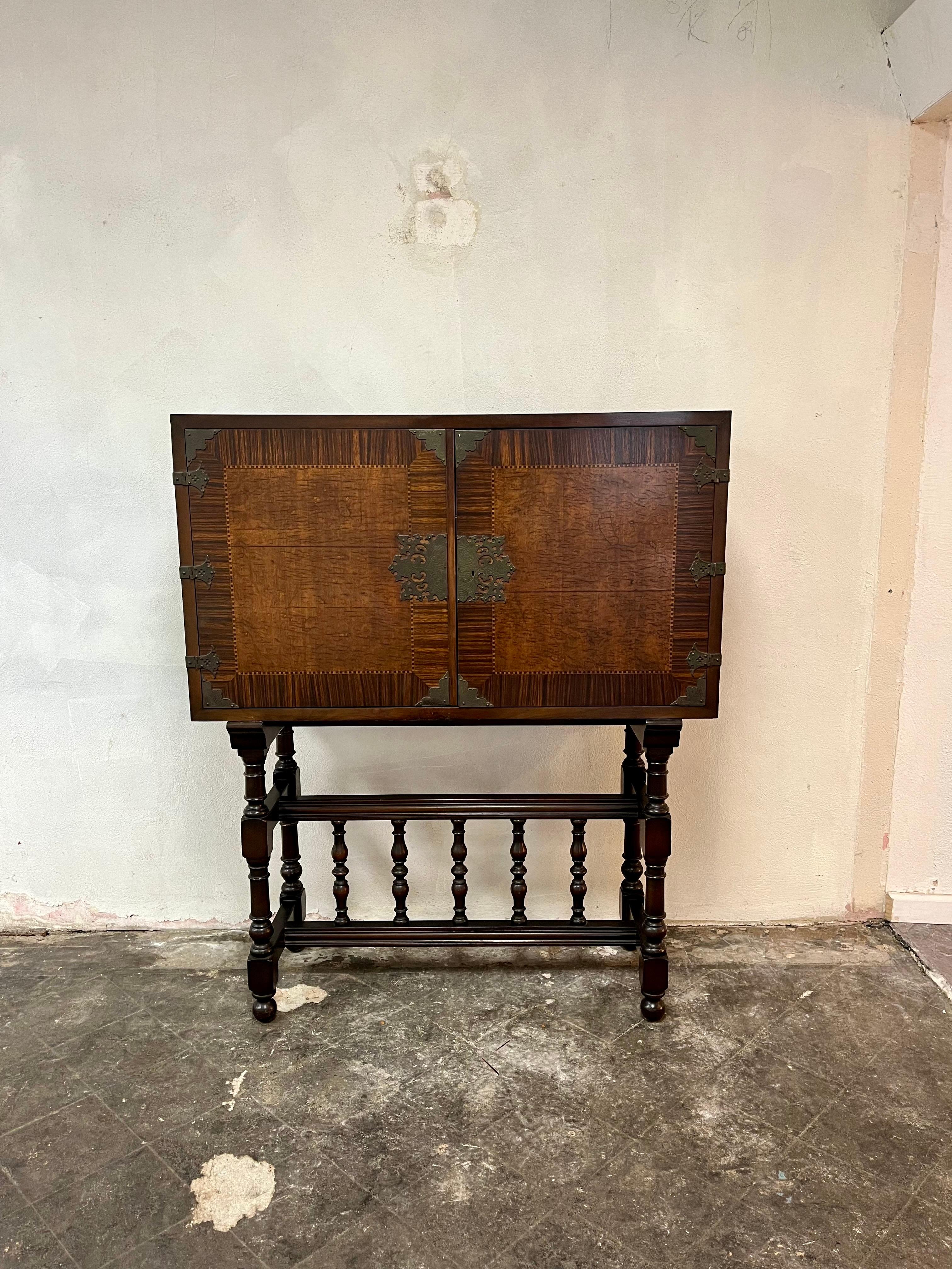 Wonderful Chinoiserie Cabinet on stand. Beautiful detail in the wood grain with different interations of walnut and classic chinoiserie metal work. Nice balance on turned legs with wide swinging doors house 2 shelves with plate grooves for ample