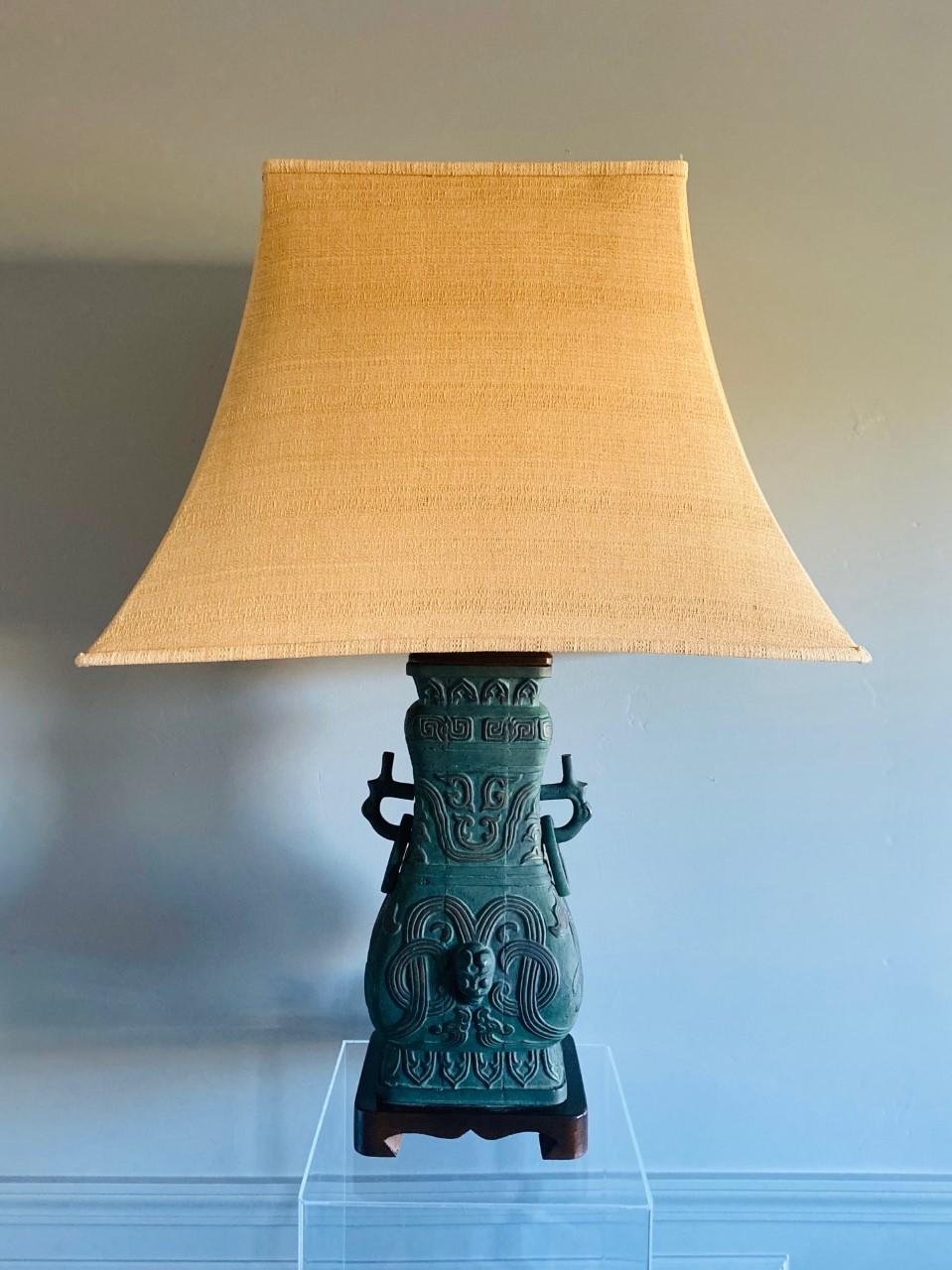 Beautiful vintage chinoiserie table lamp, Italian, midcentury. This sculptural piece is urn shaped from cast bronze and is mounted on a carved wood base. The structure is covered in a low relief chinoiserie design with a beautiful patina. The table