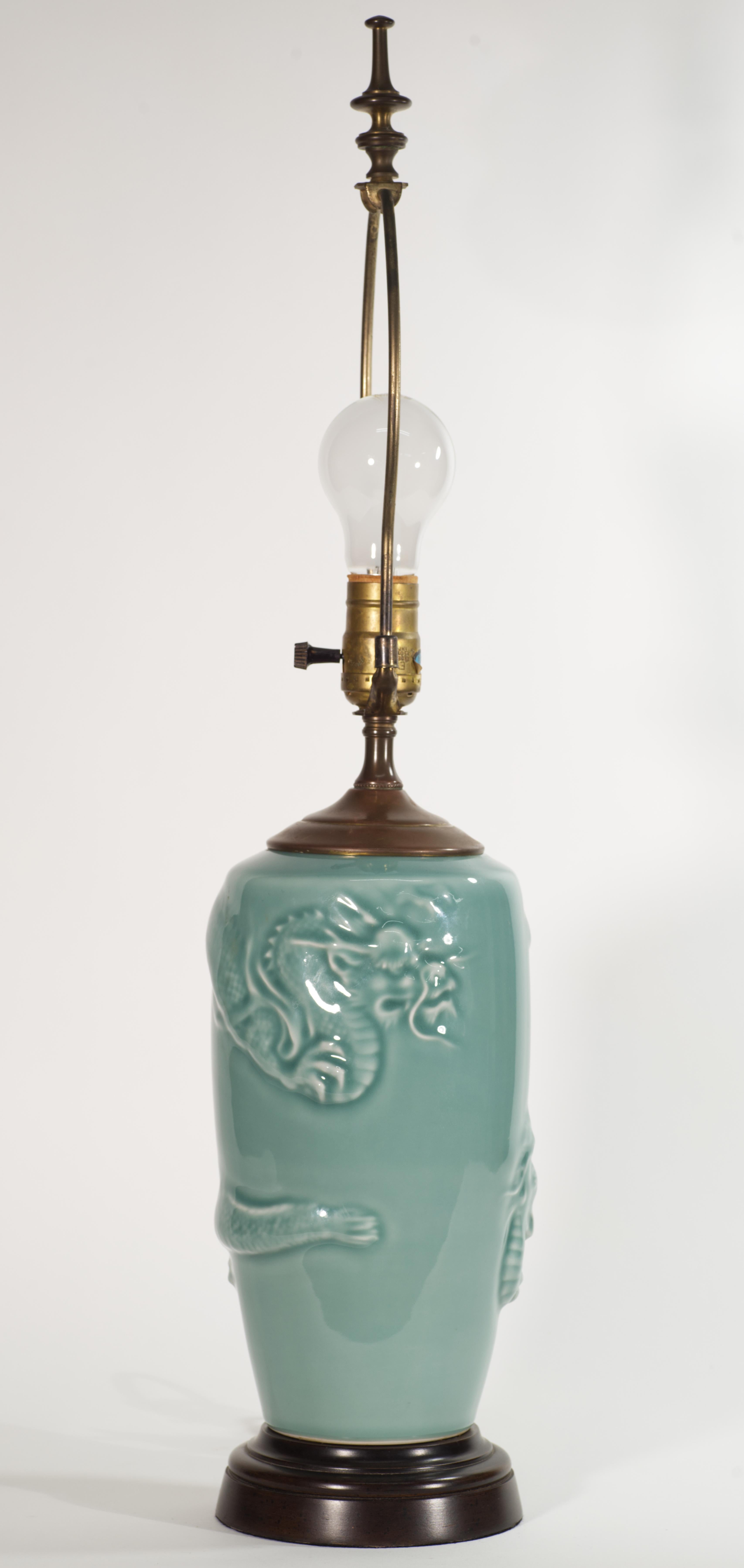  La lampe en céramique vintage présente un relief sculptural très détaillé d'un dragon asiatique traditionnel entourant le corps de la lampe. Les petits détails du corps du dragon sont accentués par les variations de lumière de la glaçure, ce qui