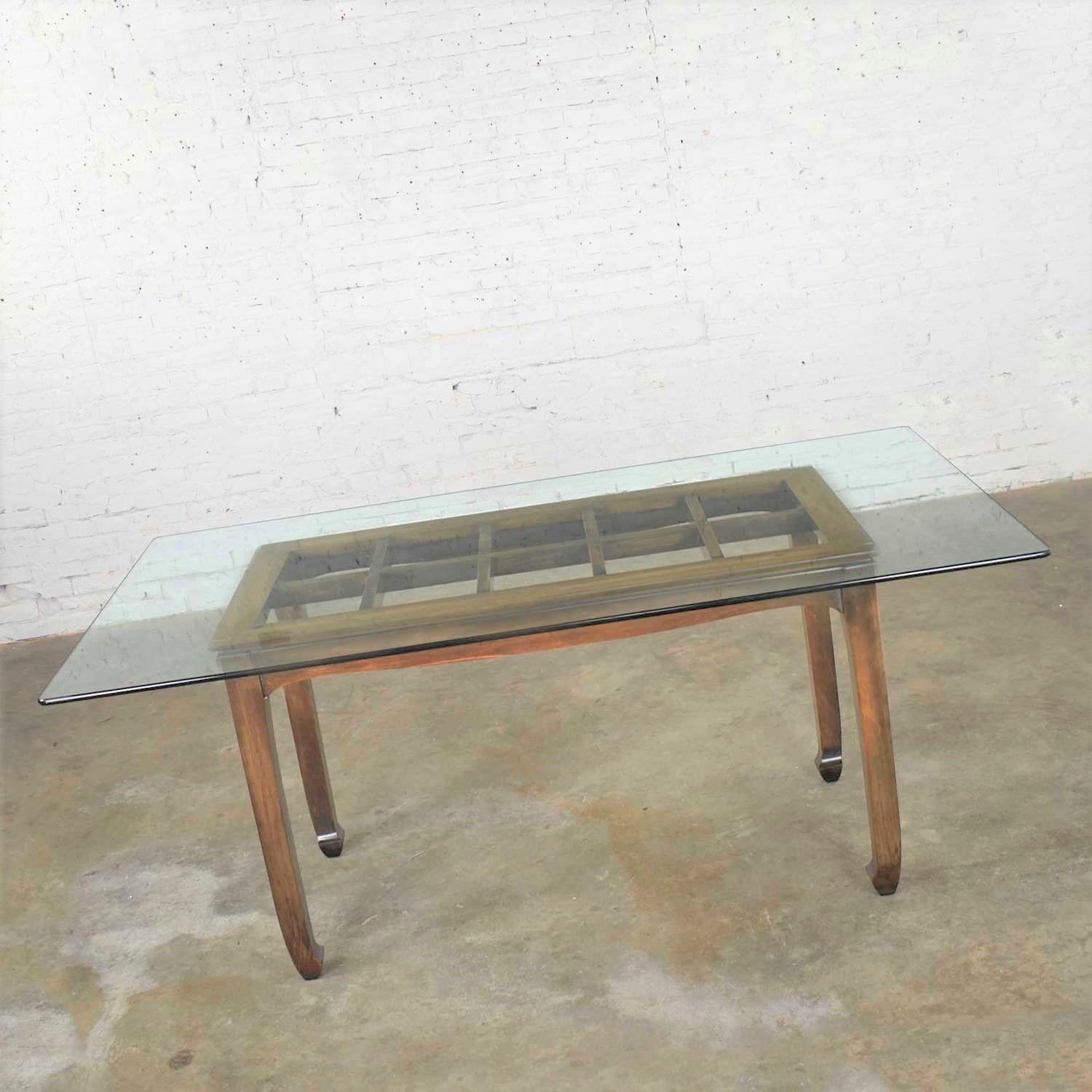 Handsome chinoiserie chow leg walnut color finish dining table with glass top. It is in wonderful vintage condition. We have done some finish restoration, but it still has a lovely patina. There has been a repair made on one of the end skirts. The