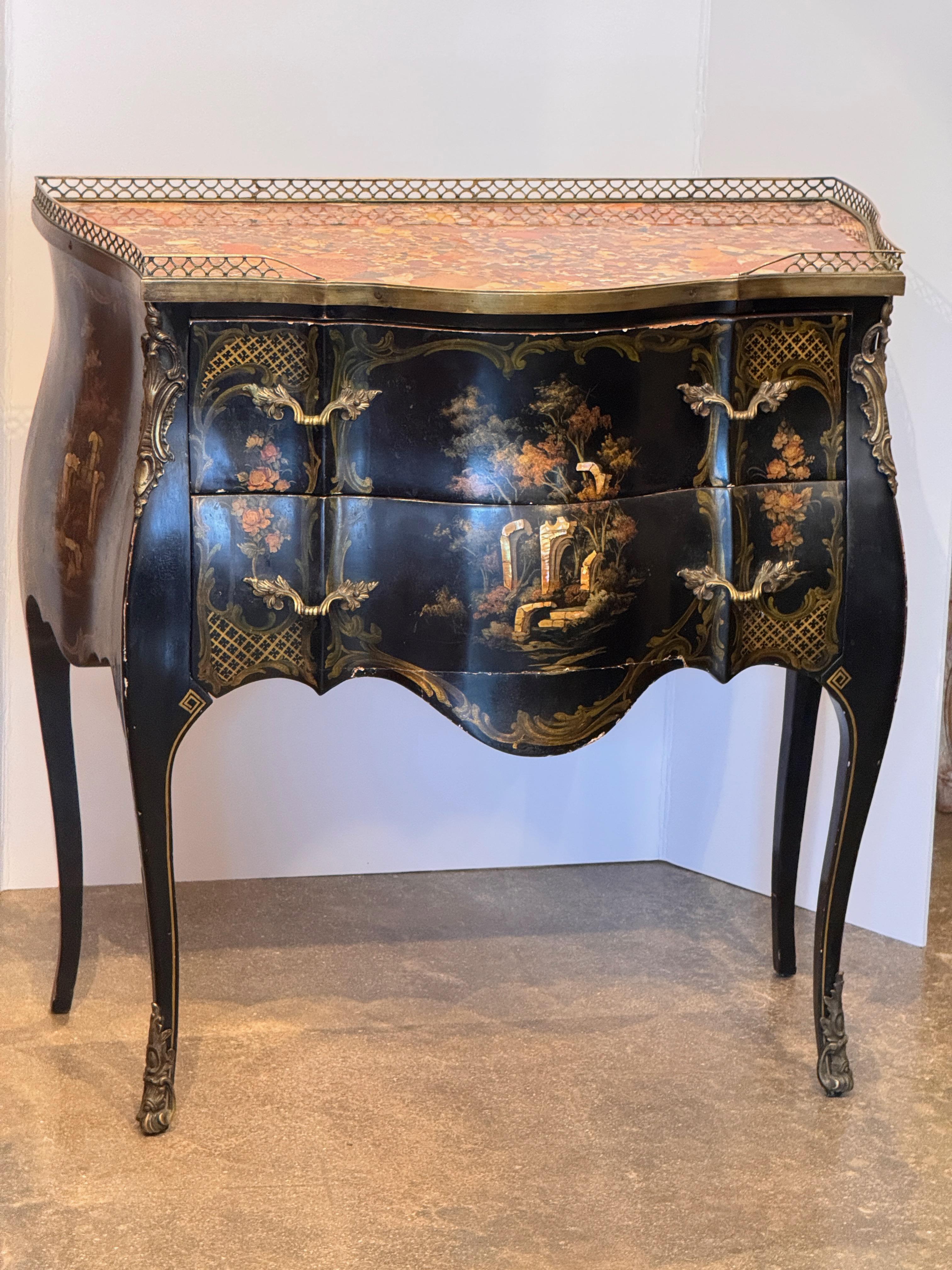 Curved-front vintage commode in the Chinoiserie style, featuring hand-painted landscape scenes over a black lacquered finish. Accented with ormolu mounts and a shaped marble top with pierced brass gallery. Two drawers with cast brass handles offer