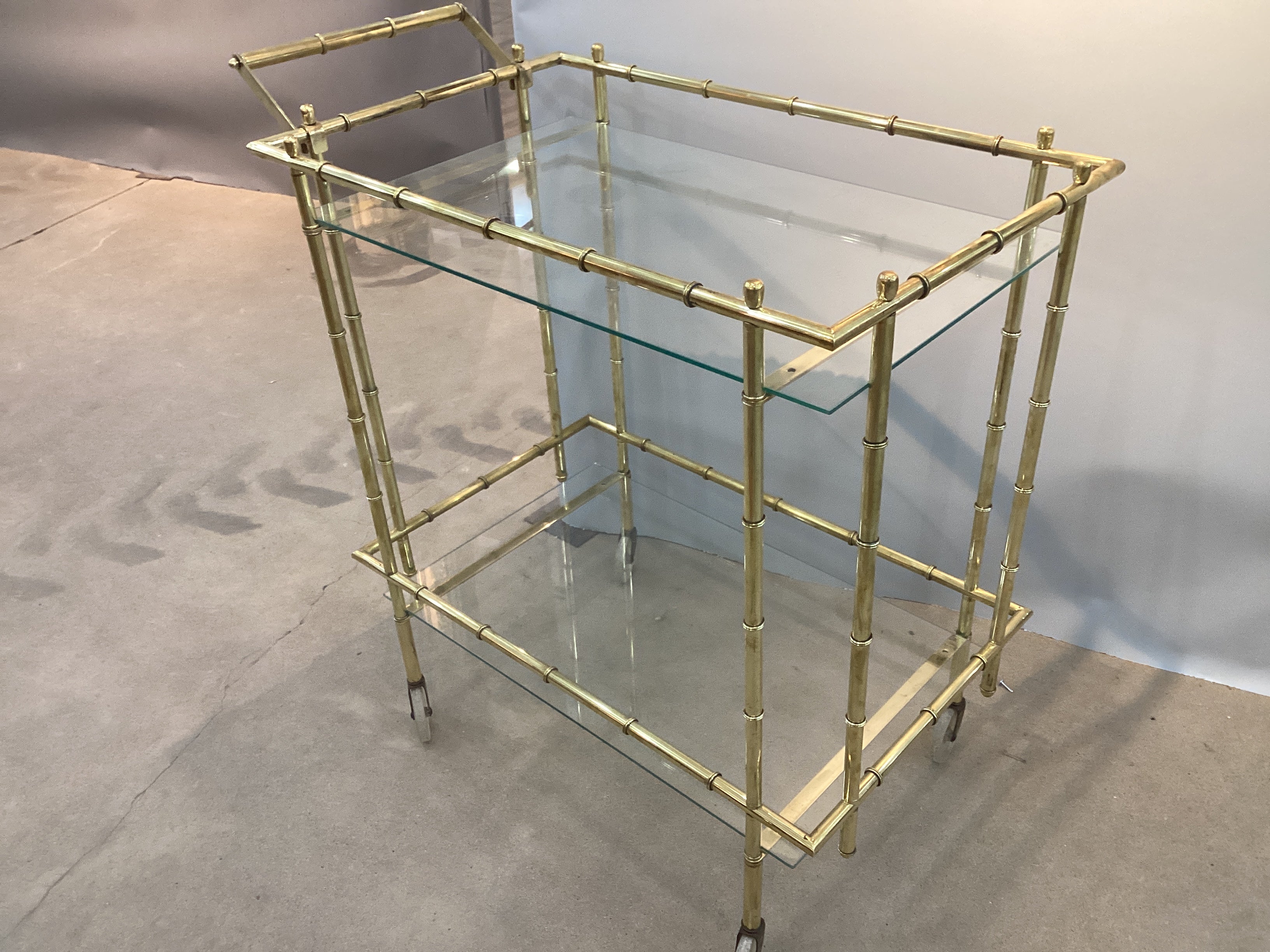 Chariot de bar à roulettes vintage en faux bambou et laiton. Récemment poli, le chariot offre suffisamment d'espace pour tous vos ustensiles de bar. Veuillez nous contacter pour des options d'expédition moins chères.