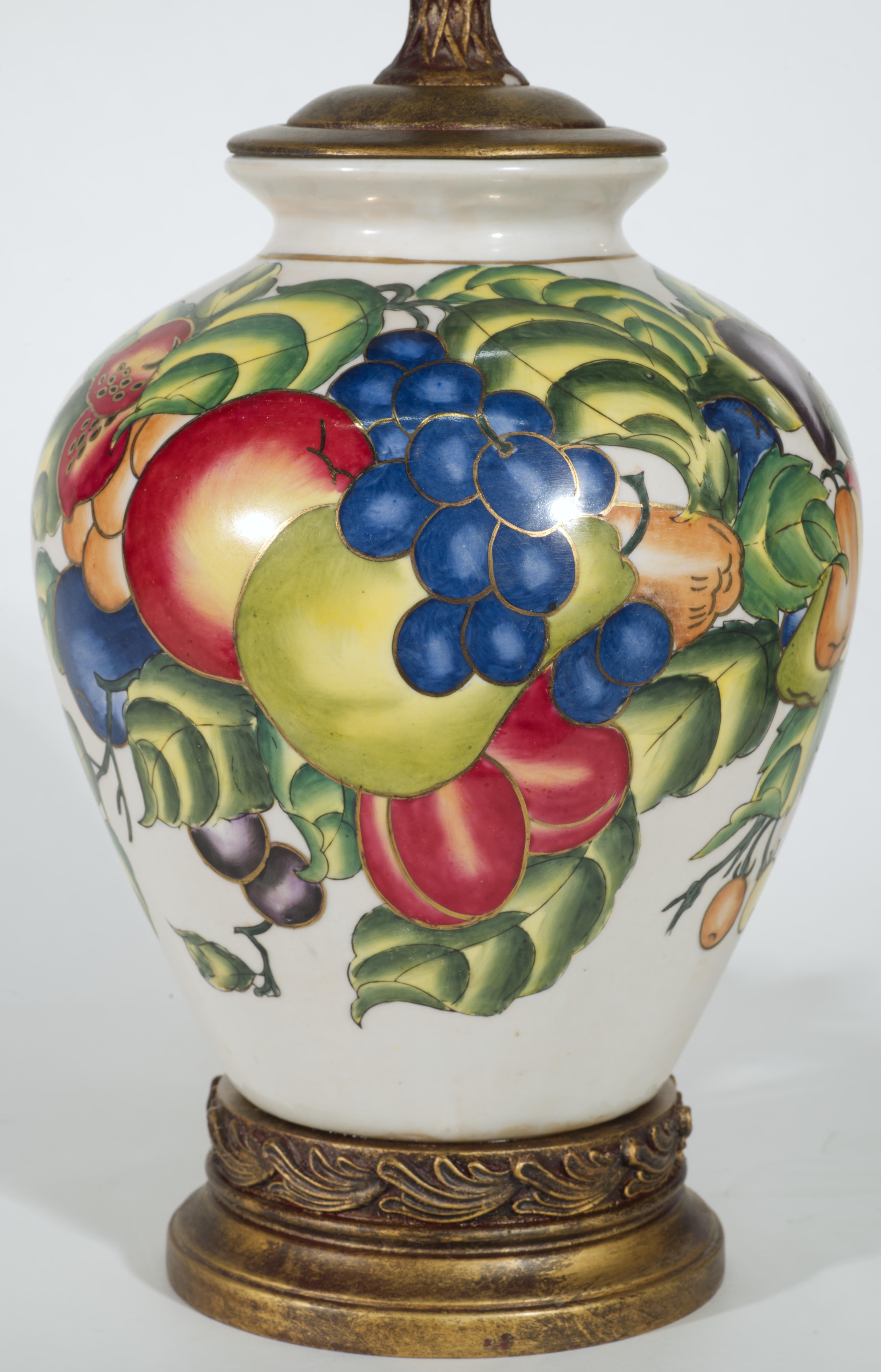  Vintage Chinoiserie urn or jar table lamp features ceramics body mounted on ornate gilded base and topped with gilded fittings and original ornate finial. The urn-shaped body is hand-painted with highly detailed oriental style decor of fruits and