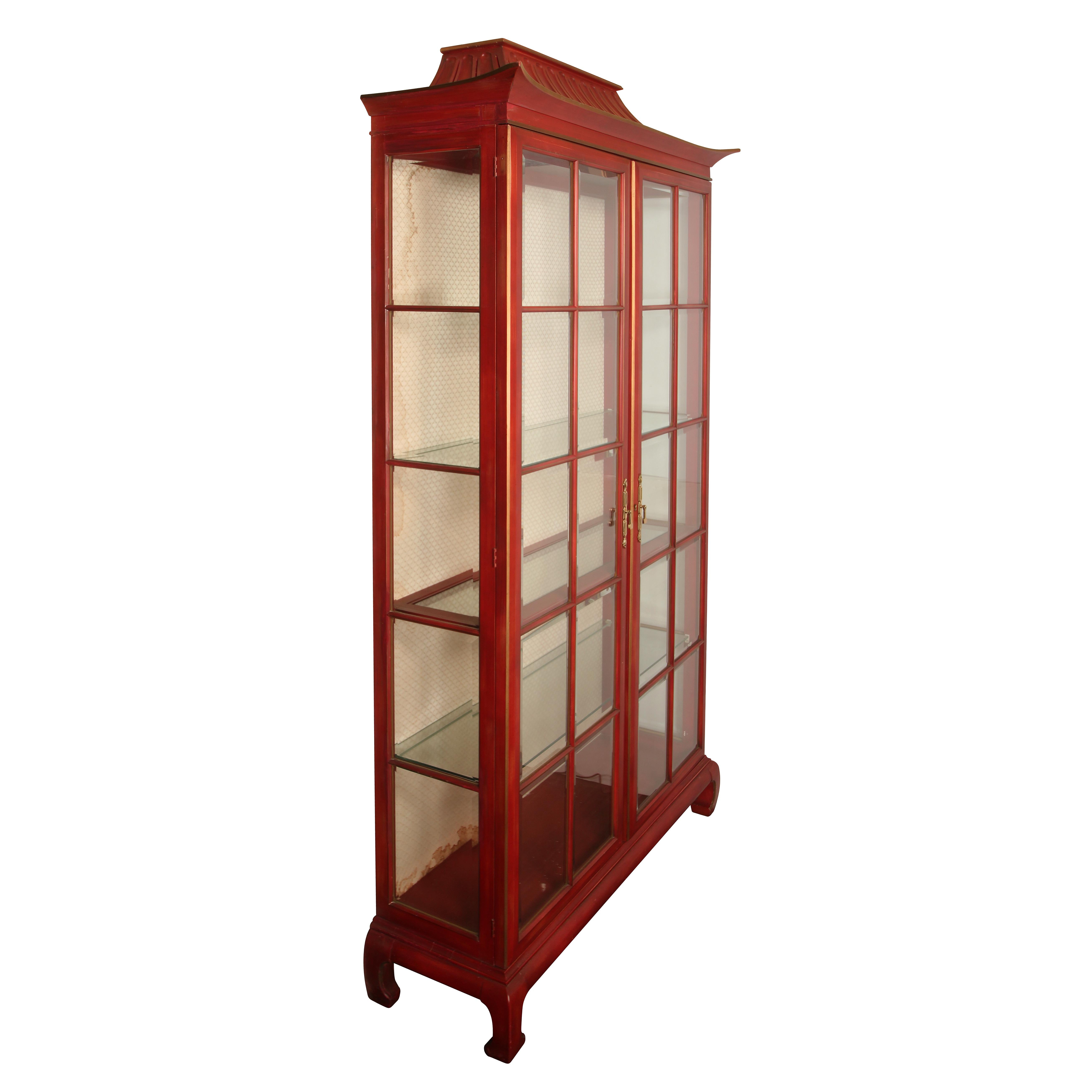 A tall, vintage chinoiserie pagoda form, red display cabinet with four shelves and a cloth lined back.