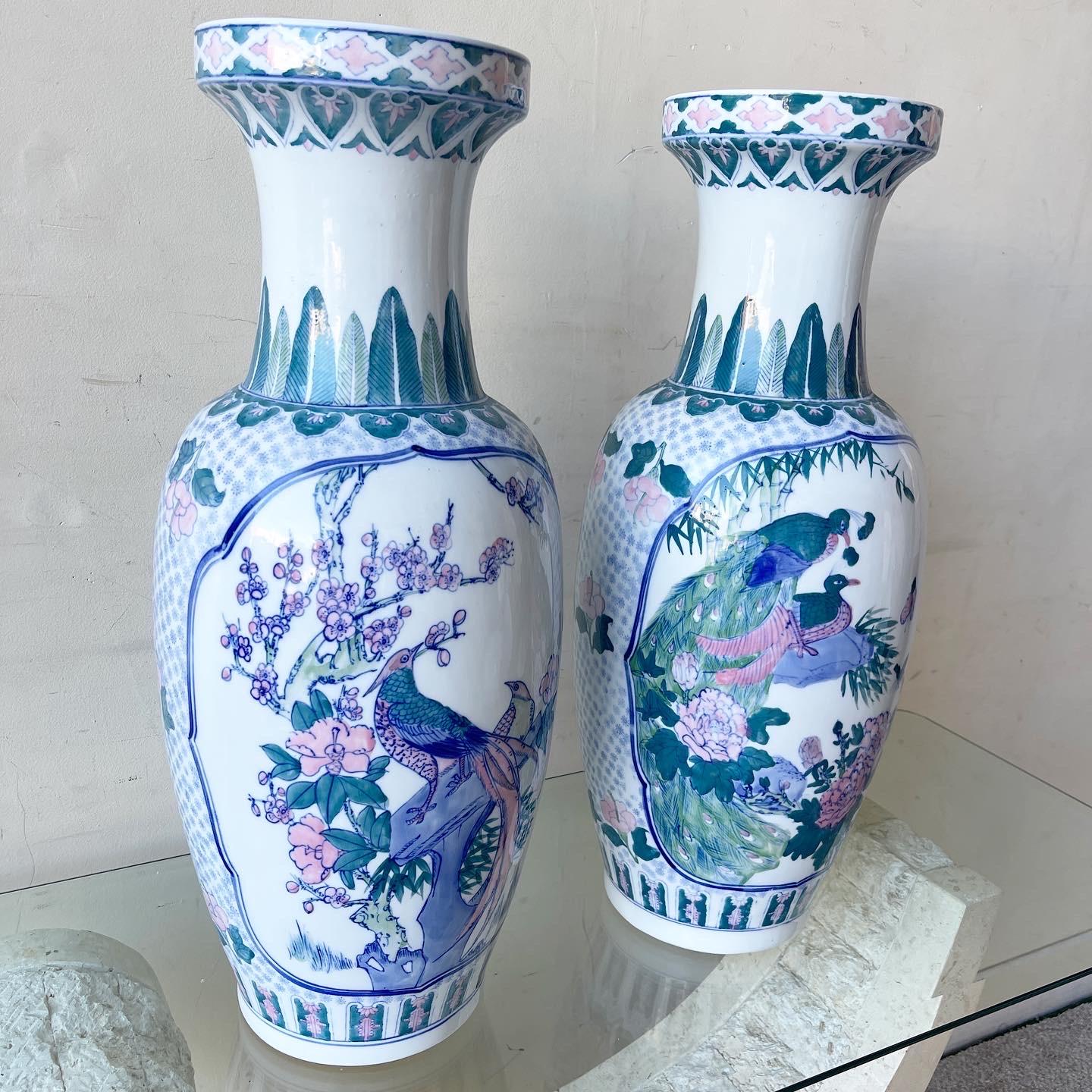 Incredible pair of vintage chinoiserie porcelain floor vases. Each feature a fantastic hand painted blue pink and green display of birds in the flowers.
