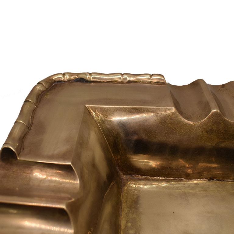 A beautiful solid brass ashtray that any grand millennial will love. Created from brass, the piece is square with rounded corners. The edges are decorated with a faux bamboo motif. Use this as a vide poche, or catchall. 

Dimensions:
8.25