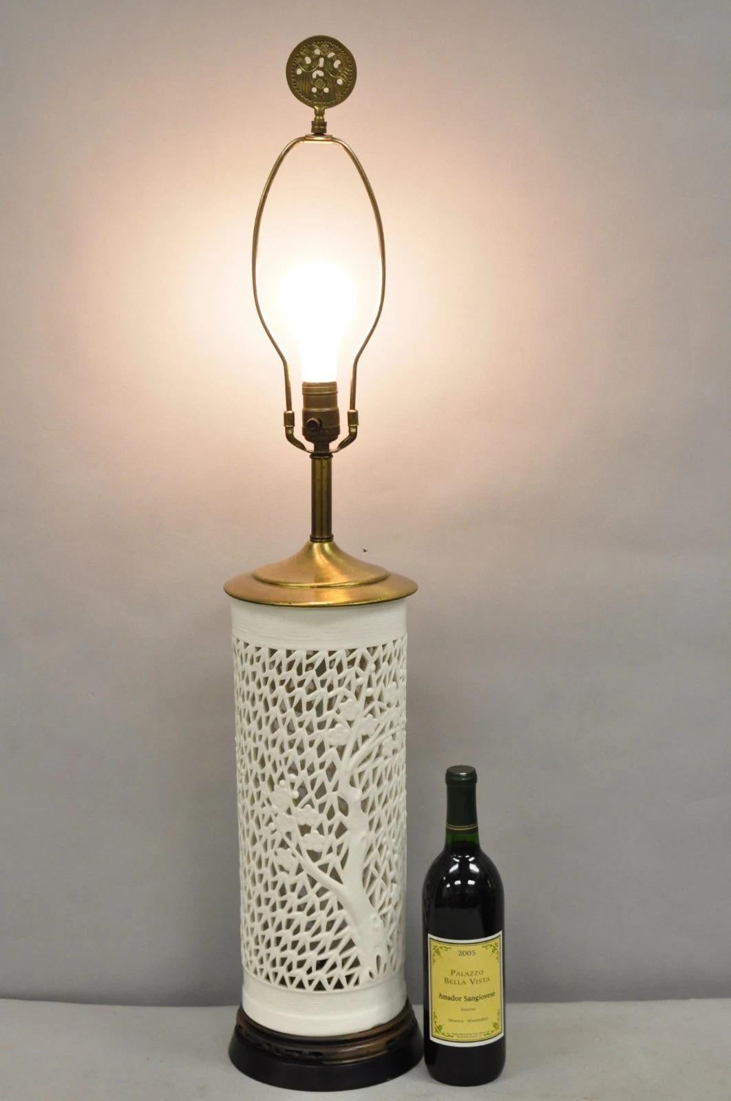 Vintage Chinoiserie White Porcelain Fretwork Cherry Blossom Tree Table Lamp On Carved Wood Base. Circa Mid 20th Century. Measurements: 37