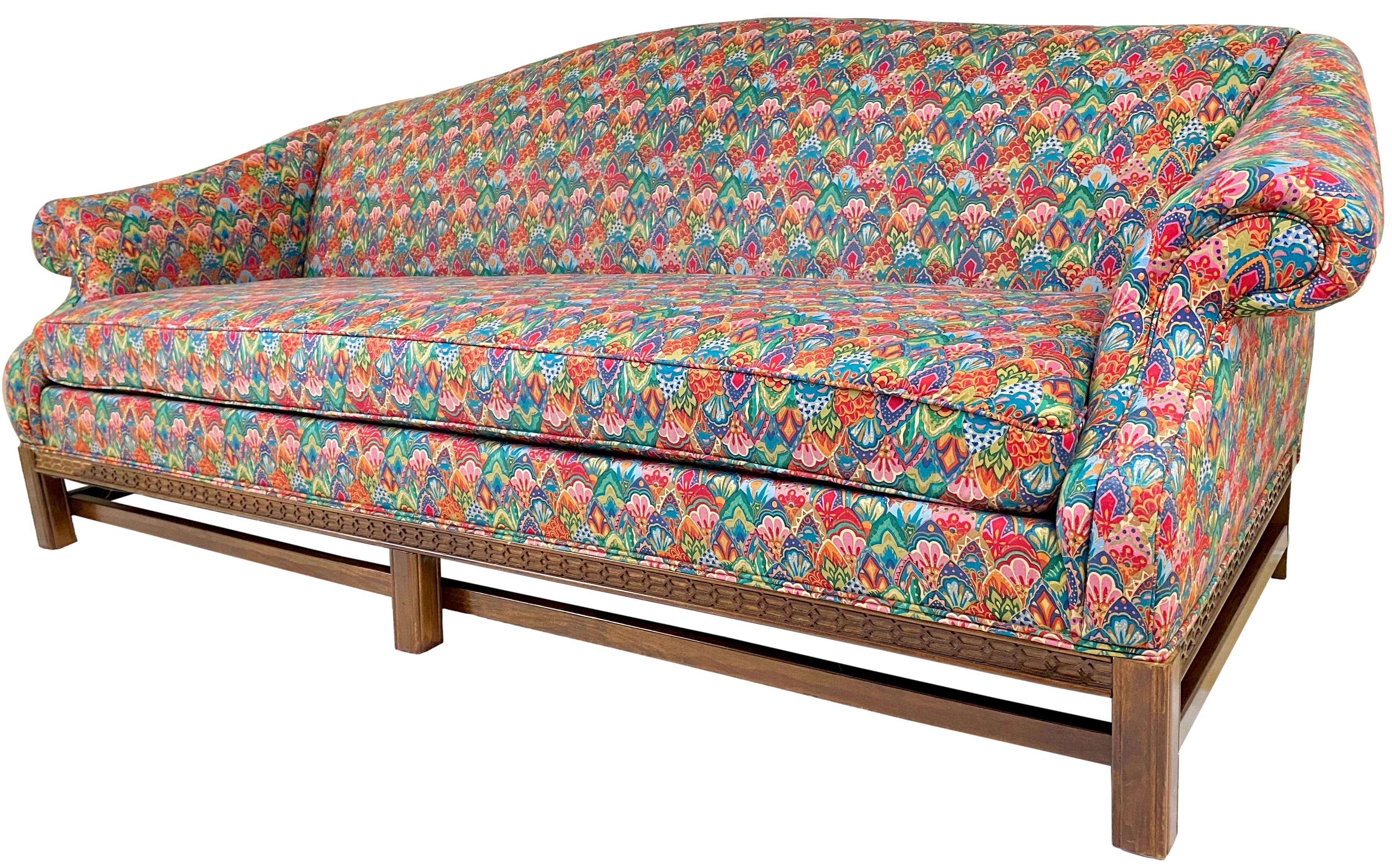 A late 20th century Chippendale style custom upholstered camelback sofa. Mahogany wood frame with lattice detail edging and Marlborough legs; upholstered in brightly patterned chintz (zippered, flippable cushion).

Dimensions: 86