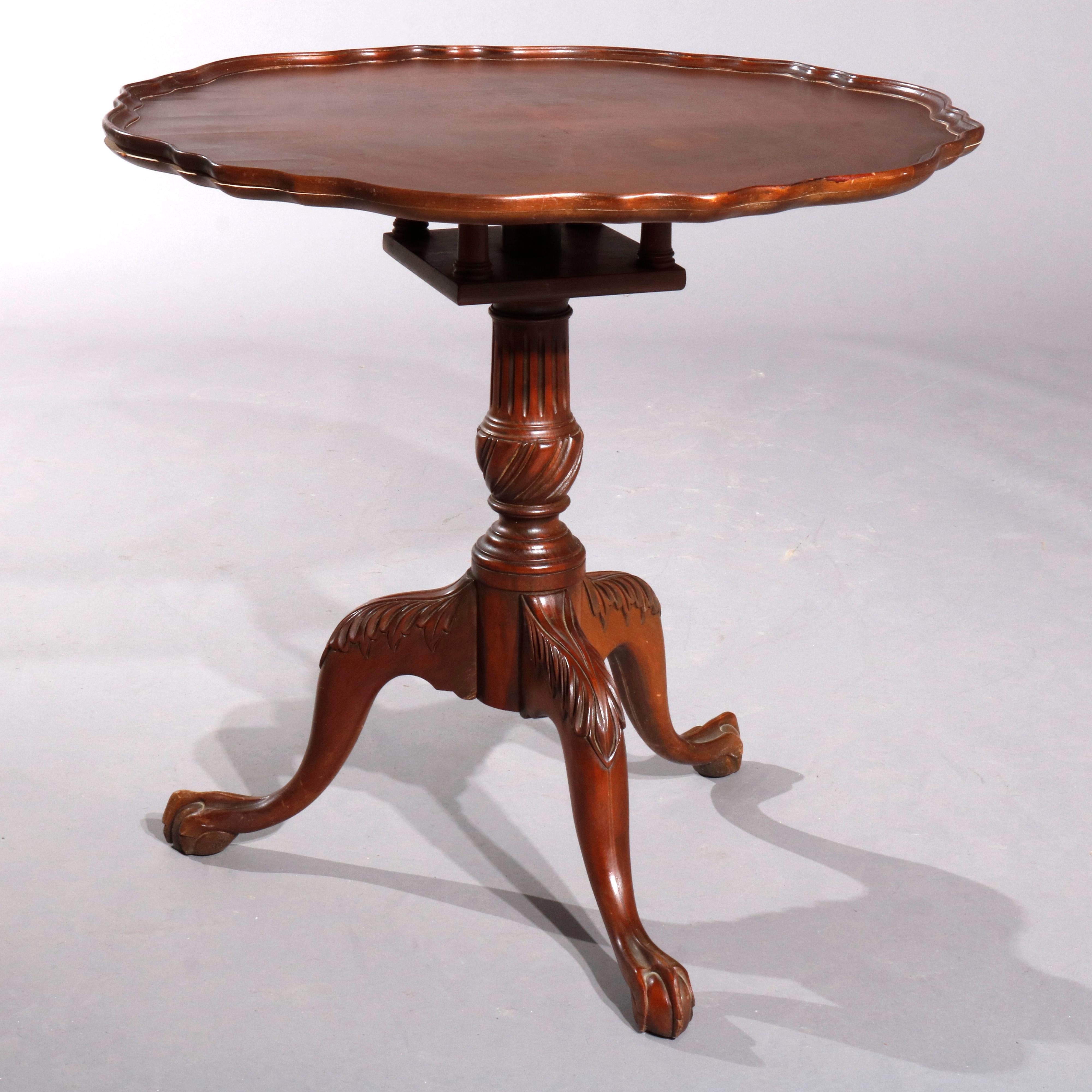 A vintage Chippendale style tea table offers mahogany construction with shaped pie crust top over reeded and foliate carved column raised on three cabriole legs terminating in claw and ball feet, c1940

Measures- 28