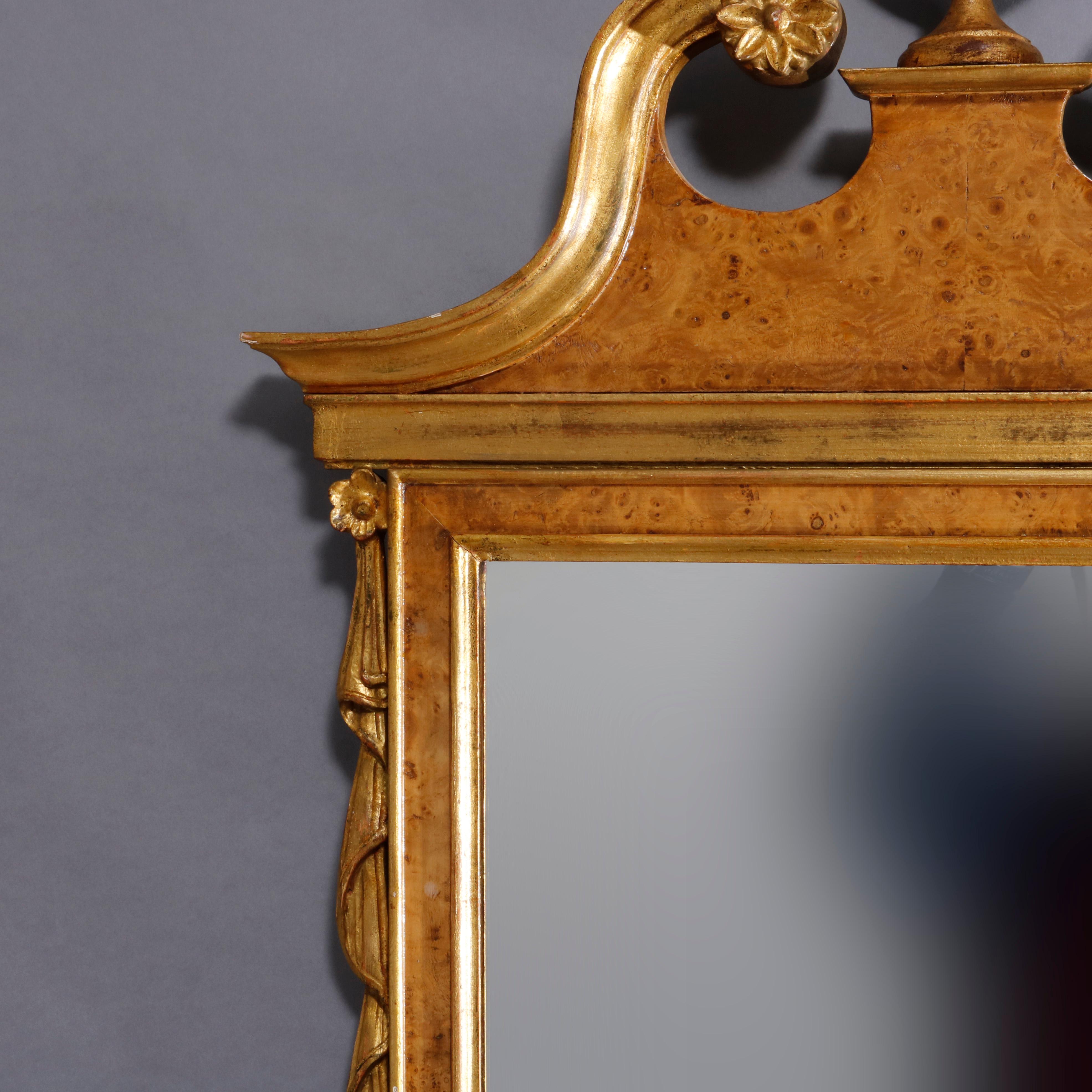 A vintage Chippendale style wall mirror offers burl walnut frame having broken arch scrolled crest with central urn having flanking drape elements, gilt highlights throughout, 20th century.

Measures: 50
