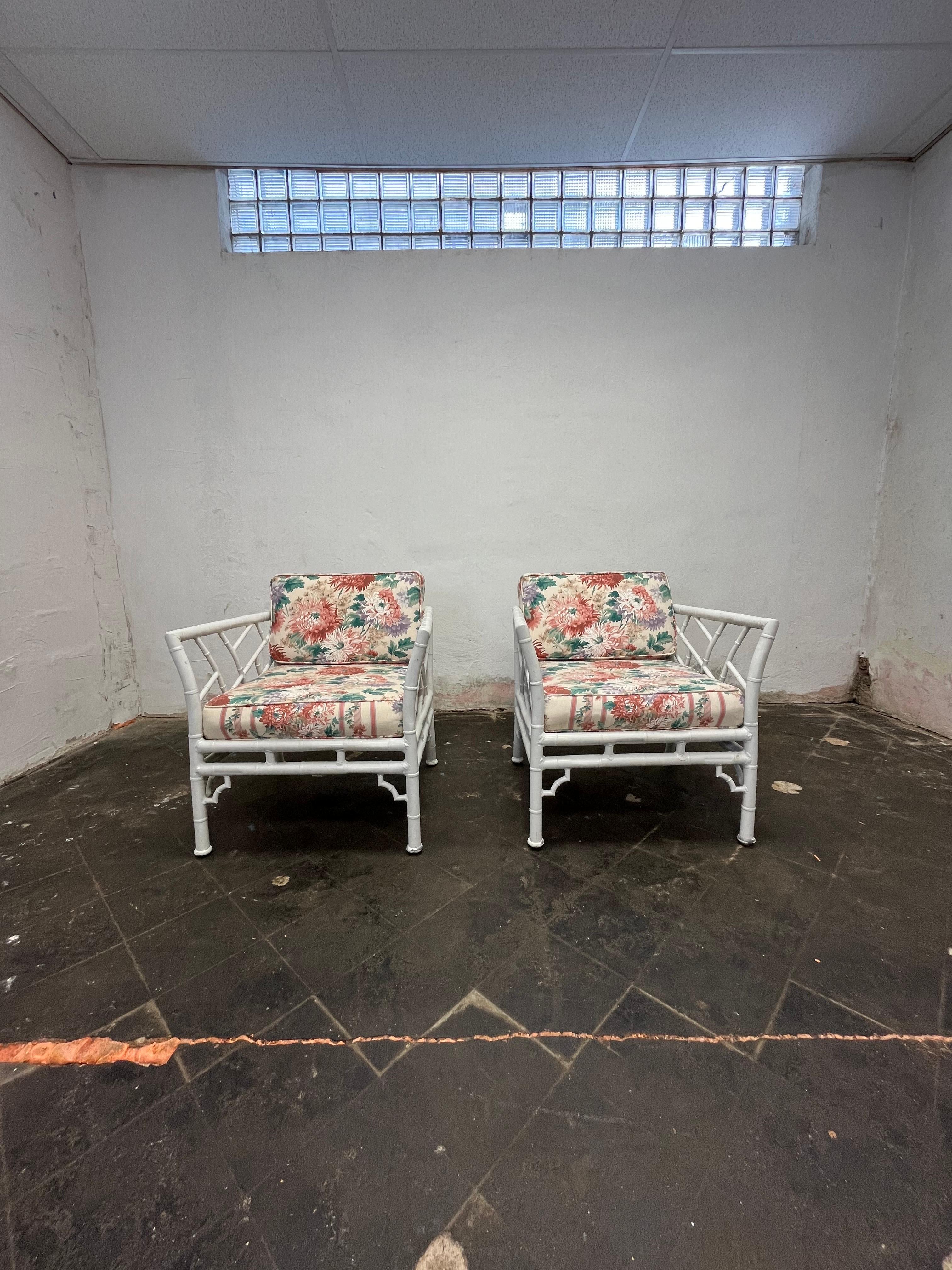 Indoor or outdoor vintage faux bamboo patio, garden or porch armchairs made of aluminum metal, painted white. Classic Chinese Chippendale style. The cushions are upholstered with a floral zippered fabric. Under the seat cushions are elasticized