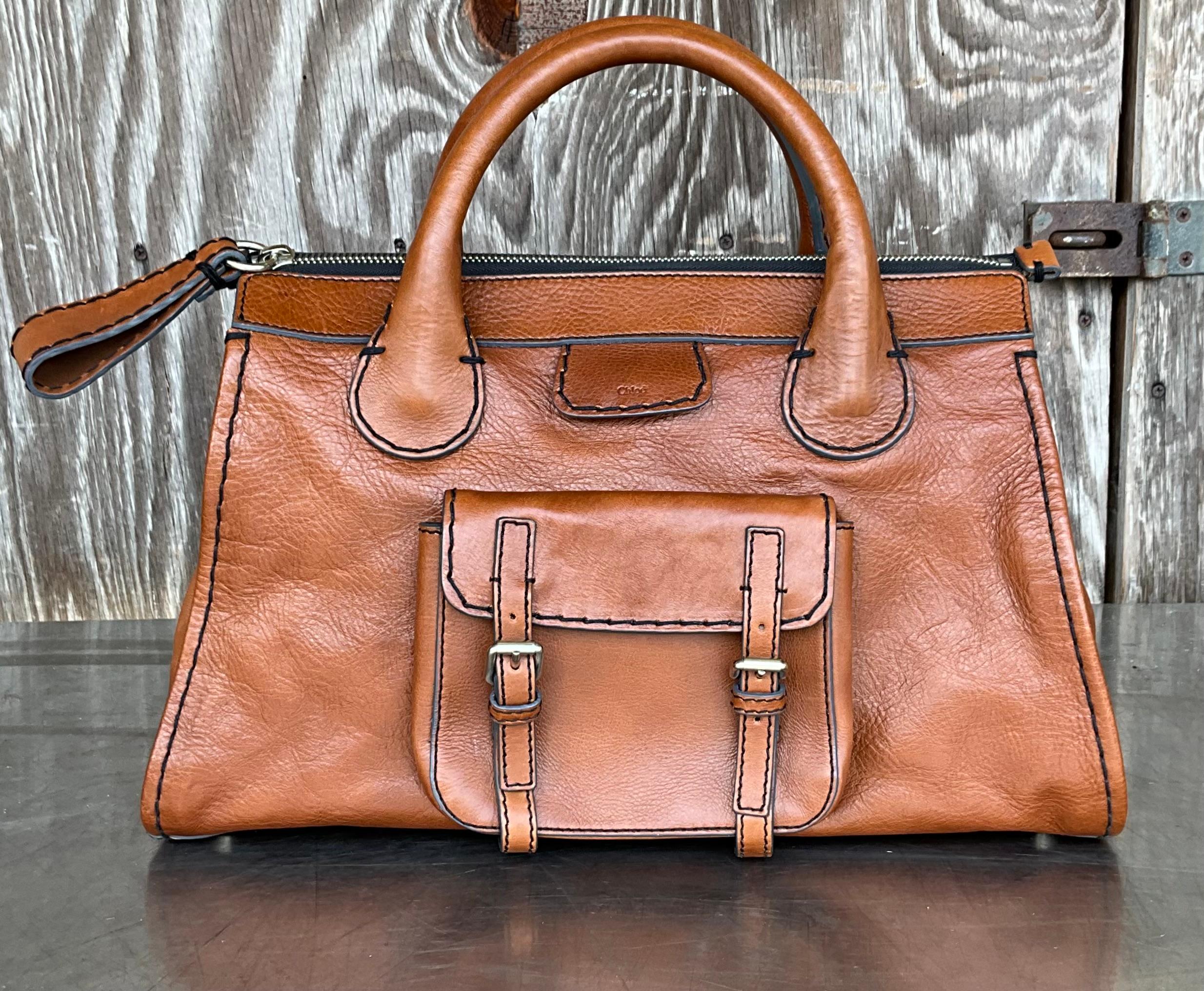 The Vintage Chloé Edith Leather Tote is crafted from supple, high-quality leather, typically featuring a rich, deep color such as brown, black, or beige, that improves with age and develops a beautiful patina over time. The leather is soft yet