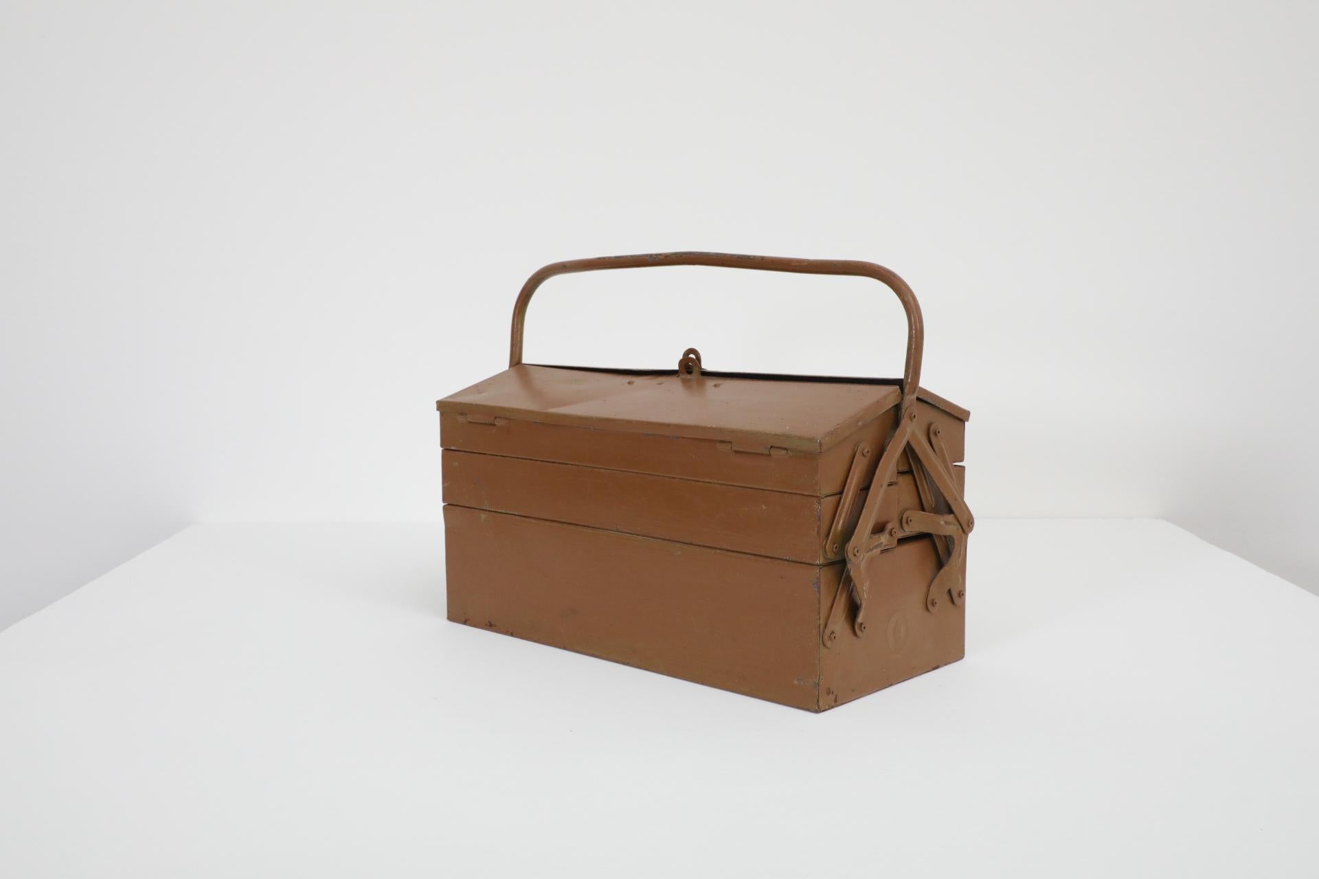 Vintage chocolate brown metal tool box with green interior, handle and stacking trays. In original condition with visible wear, including enameled loss, discoloration and scratches. Wear is consistent with its age and use. 
