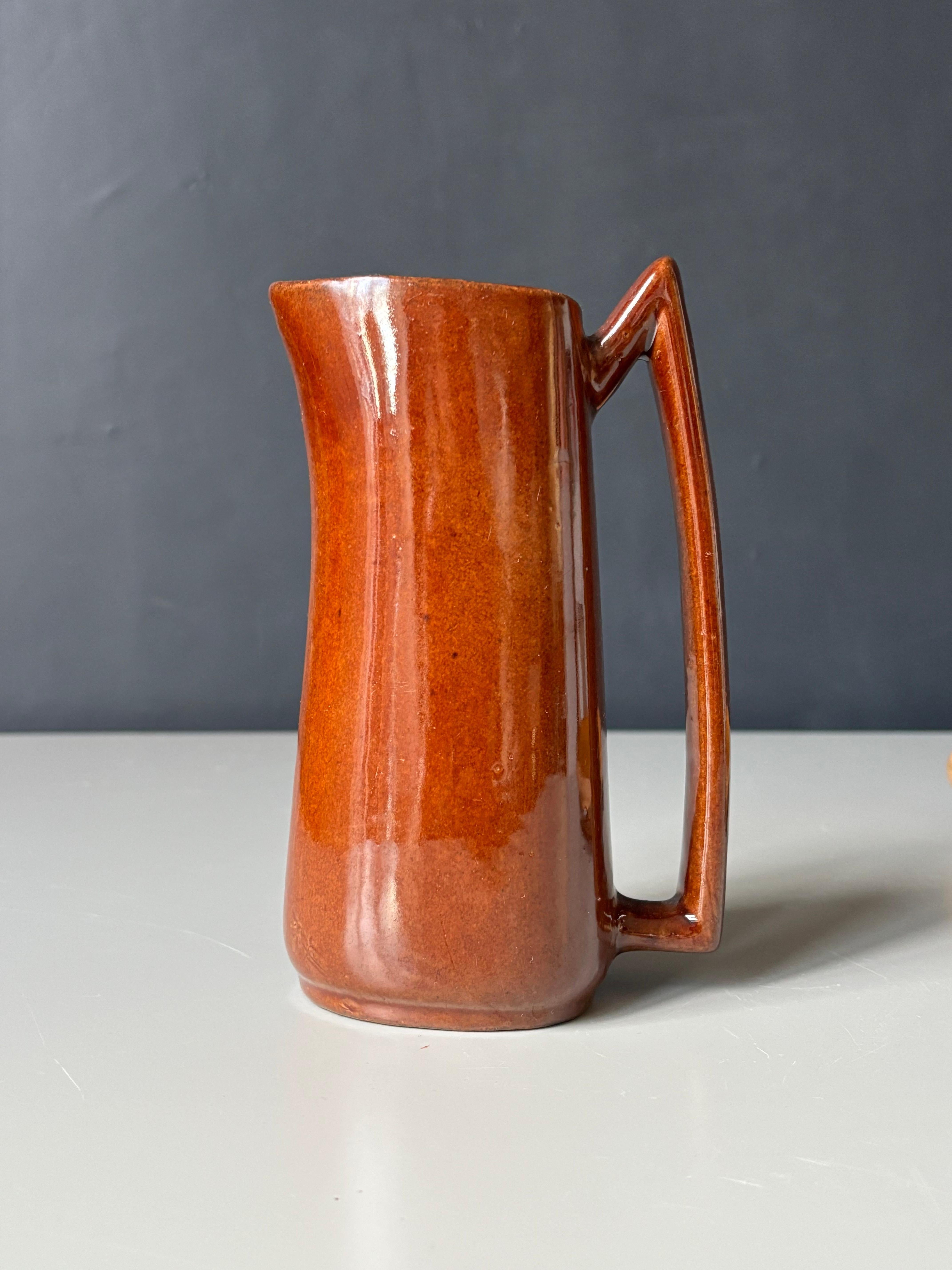 Modernistische Keramikkrugvase mit ausgeprägt kantigem, spitzem Henkel. Außen eine dicke glänzende schokoladenbraune Glasur, innen eine hellere braune Glasur. Unter dem Sockel signiert. 
Schöner Vintage-Zustand. 