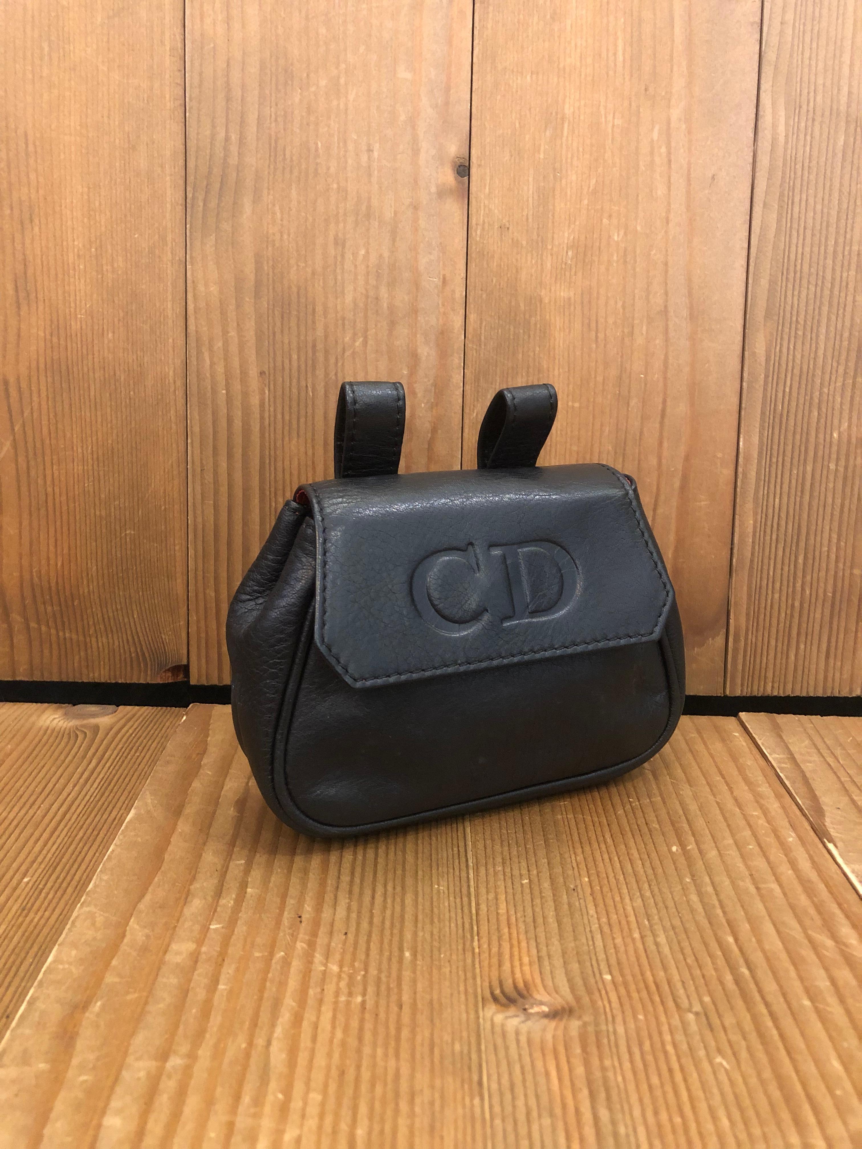This vintage CHRISTIAN DIOR Mini belt bag is crafted of calfskin leather in black. Front flap magnetic snap closure opens to a red lambskin interior. Made in Spain. Bag measures approximately 3.5/4.5 x 4 x 1.25 inches. Comes with replacement belt