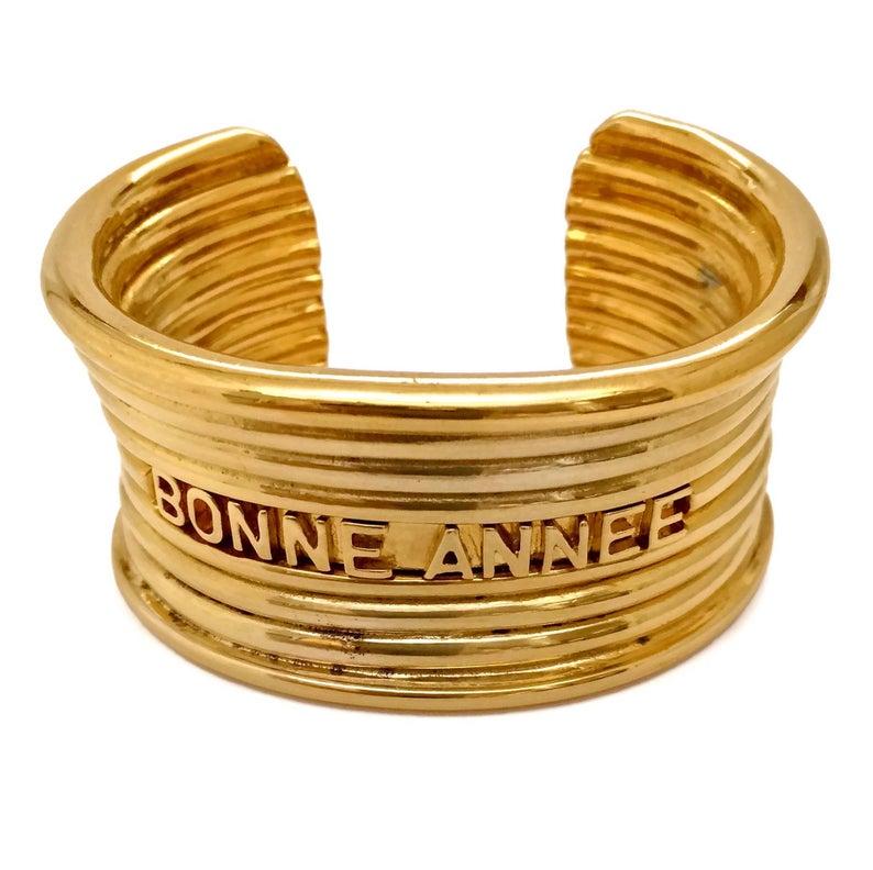 Vintage CHRISTIAN DIOR Bonne Annee Ribbed Cuff Bracelet

Measurements:
Height: 1.45 inches (3.7 cms)
Inside Circumference: 6.88 inches (17.5 cms)

Features:
- 100% Authentic CHRISTIAN DIOR.
- Ribbed wide cuff.
- Embossed BONNE ANNEE (HAPPY NEW YEAR)