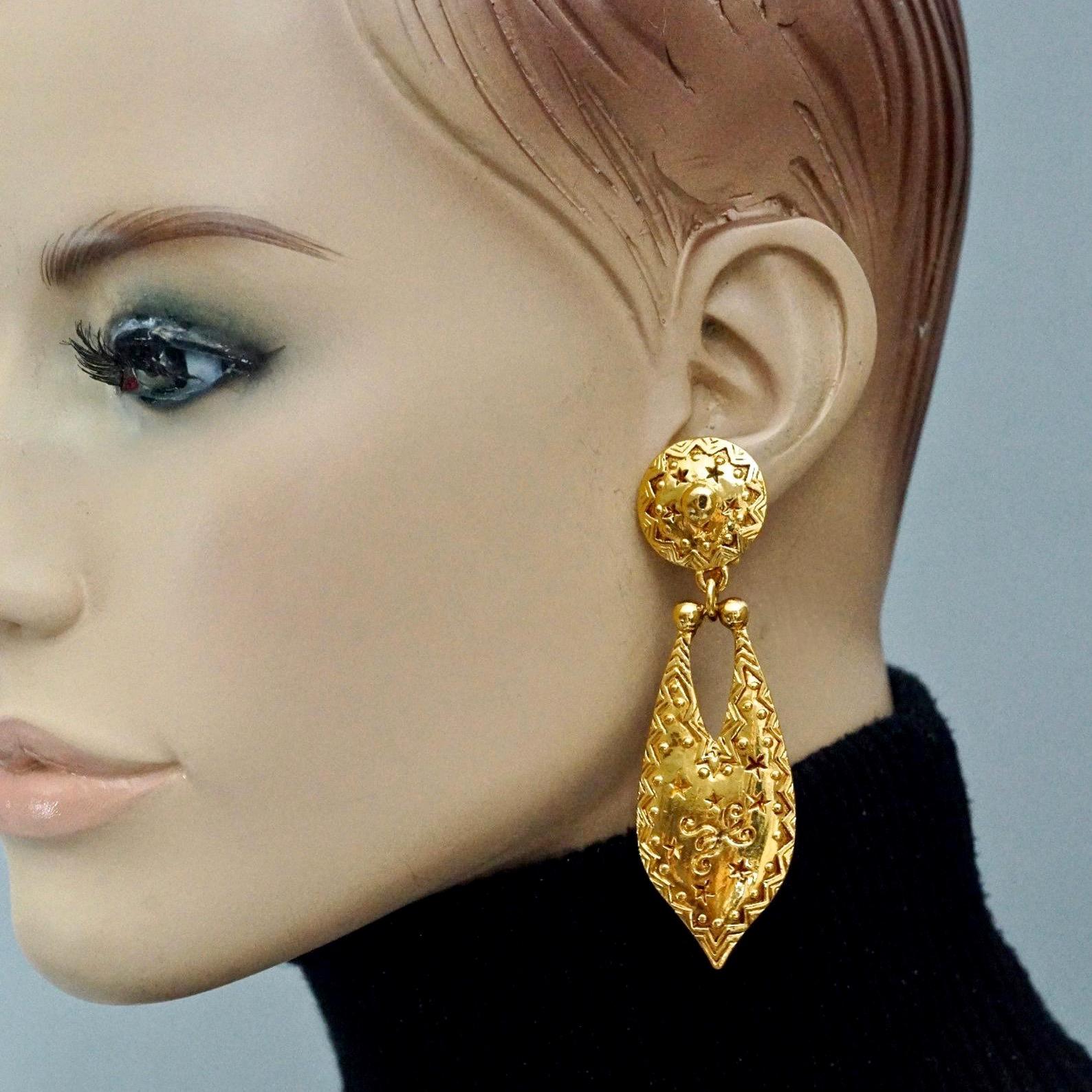 Vintage CHRISTIAN DIOR BOUTIQUE Ethnic Dangling Earrings

Measurements:
Height: 3.18 inches (8.1 cm)
Width: 0.98 inch (2.5 cm)
Weight per Earring: 19 grams

Features:
- 100% Authentic CHRISTIAN DIOR.
- Ethnic pattern dangling earrings.
- Gold