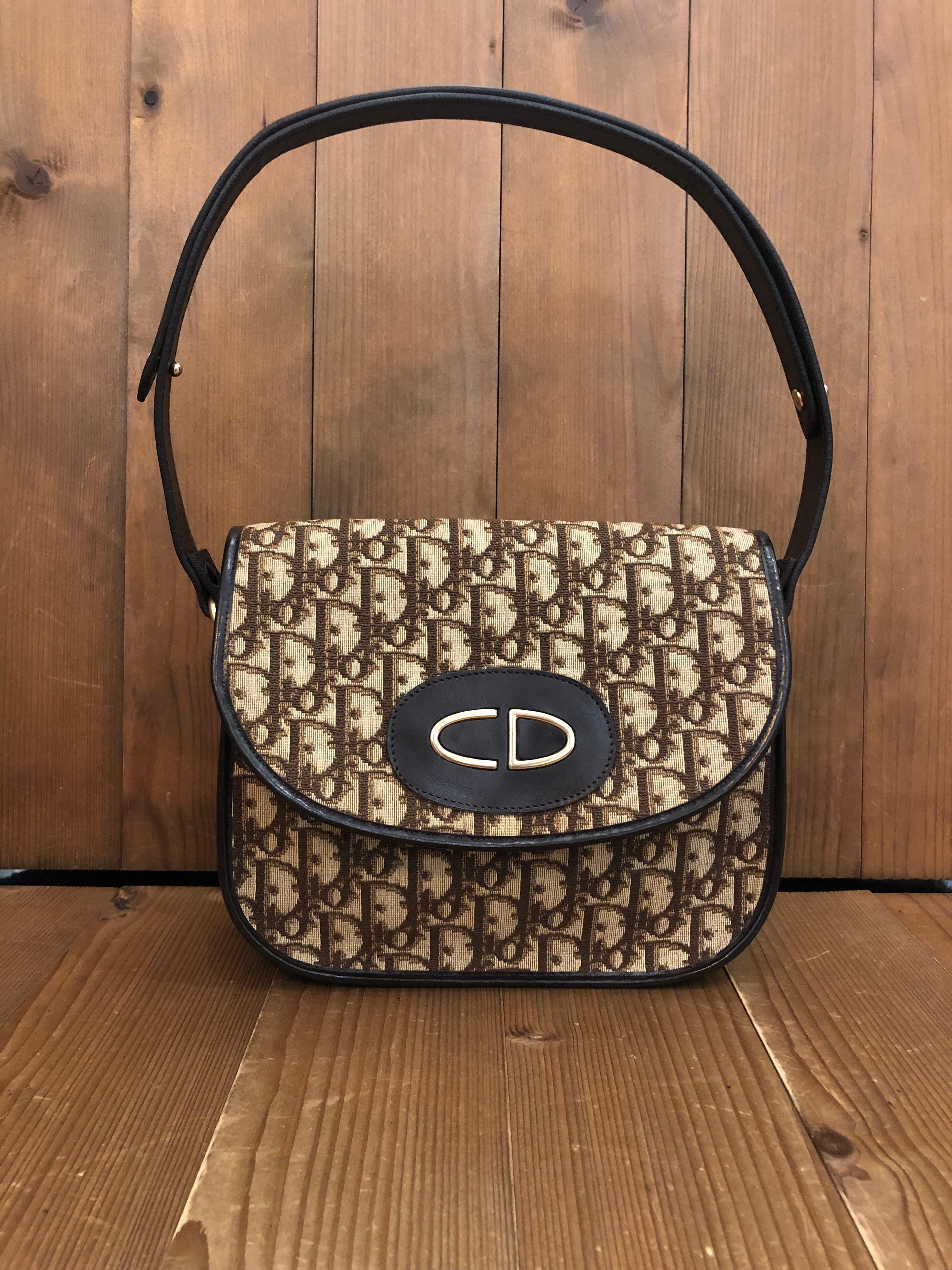 1970s Christian Dior shoulder bag in brown trotter jacquard and leather. Front snap fastening closure opens to a coated interior in brown. Made in France. Measures approximately 9 x 6.5 x 2.75 inches Strap drop 14 inches at its longest. 

Condition