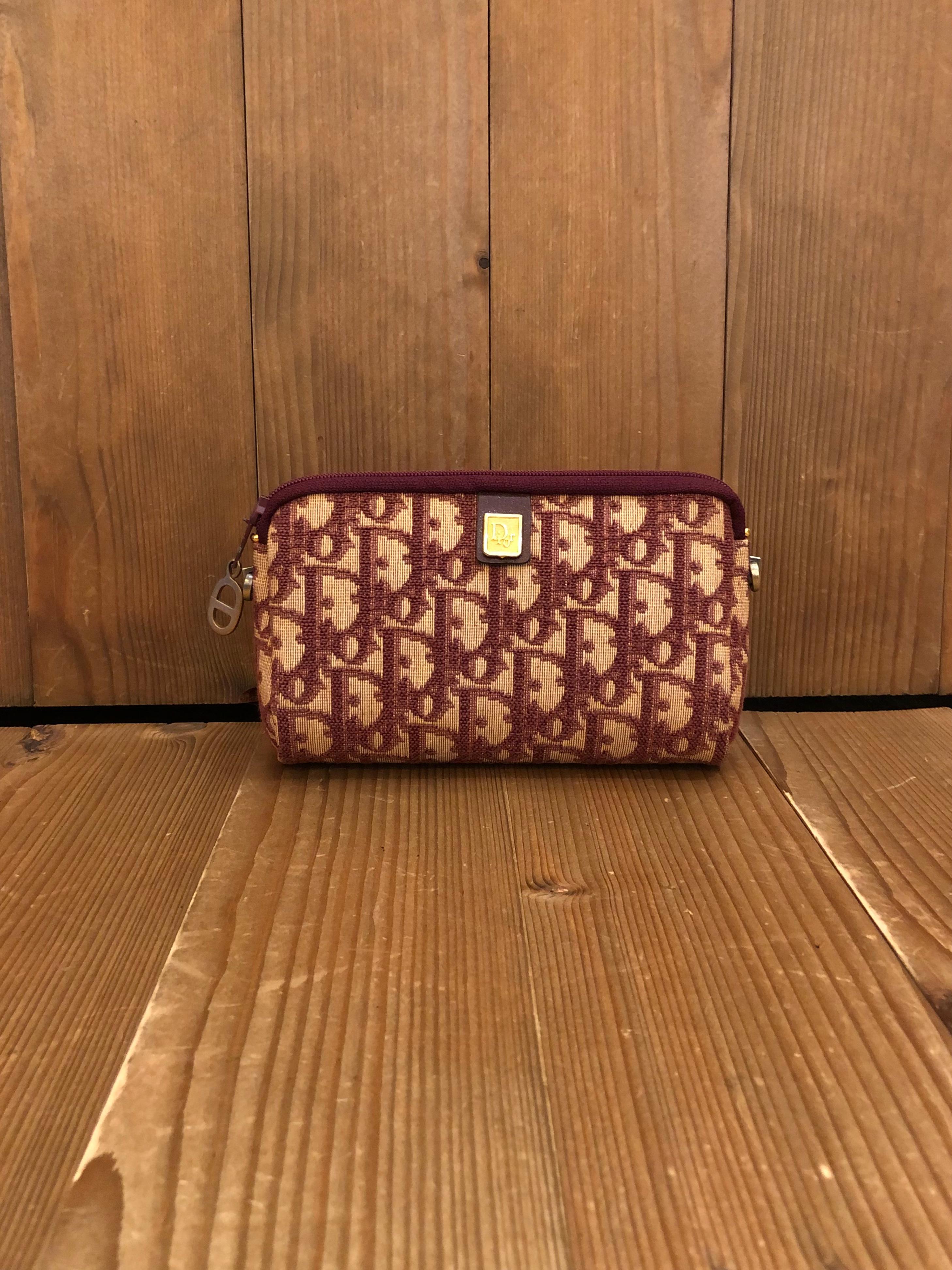 This 1970s Vintage CHRISTIAN DIOR mini pouch is crafted of Dior signature Trotter jacquard in burgundy. Top zipper closure opens to a coated interior in burgundy. Made in France. Third party hardware added on the sides to secure a gold toned chain.