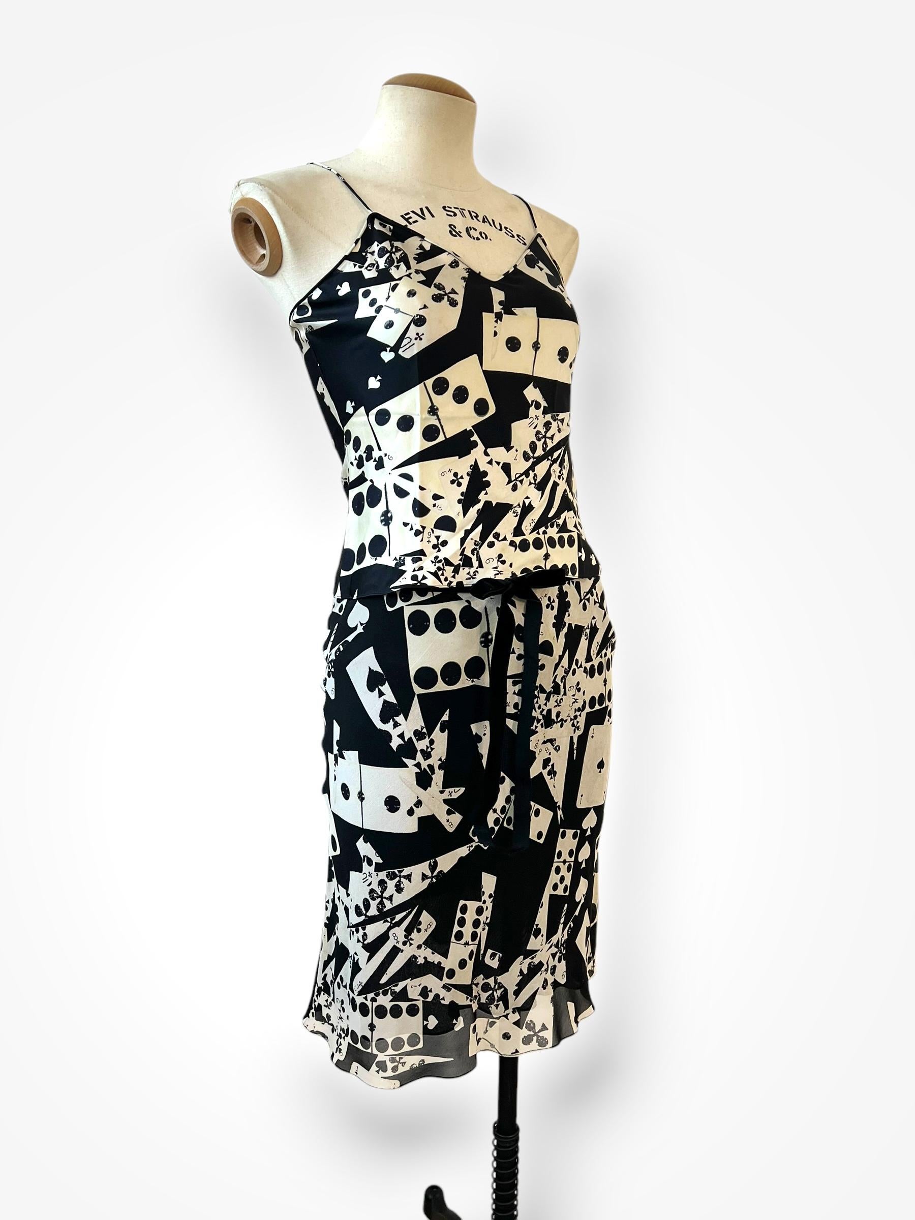 Entrez dans l'univers fantaisiste de John Galliano avec cet ensemble deux pièces en soie de la collection automne-hiver 2001 de Christian Dior. L'ensemble, qui arbore le motif emblématique des cartes à jouer et des dominos, comprend un haut de style