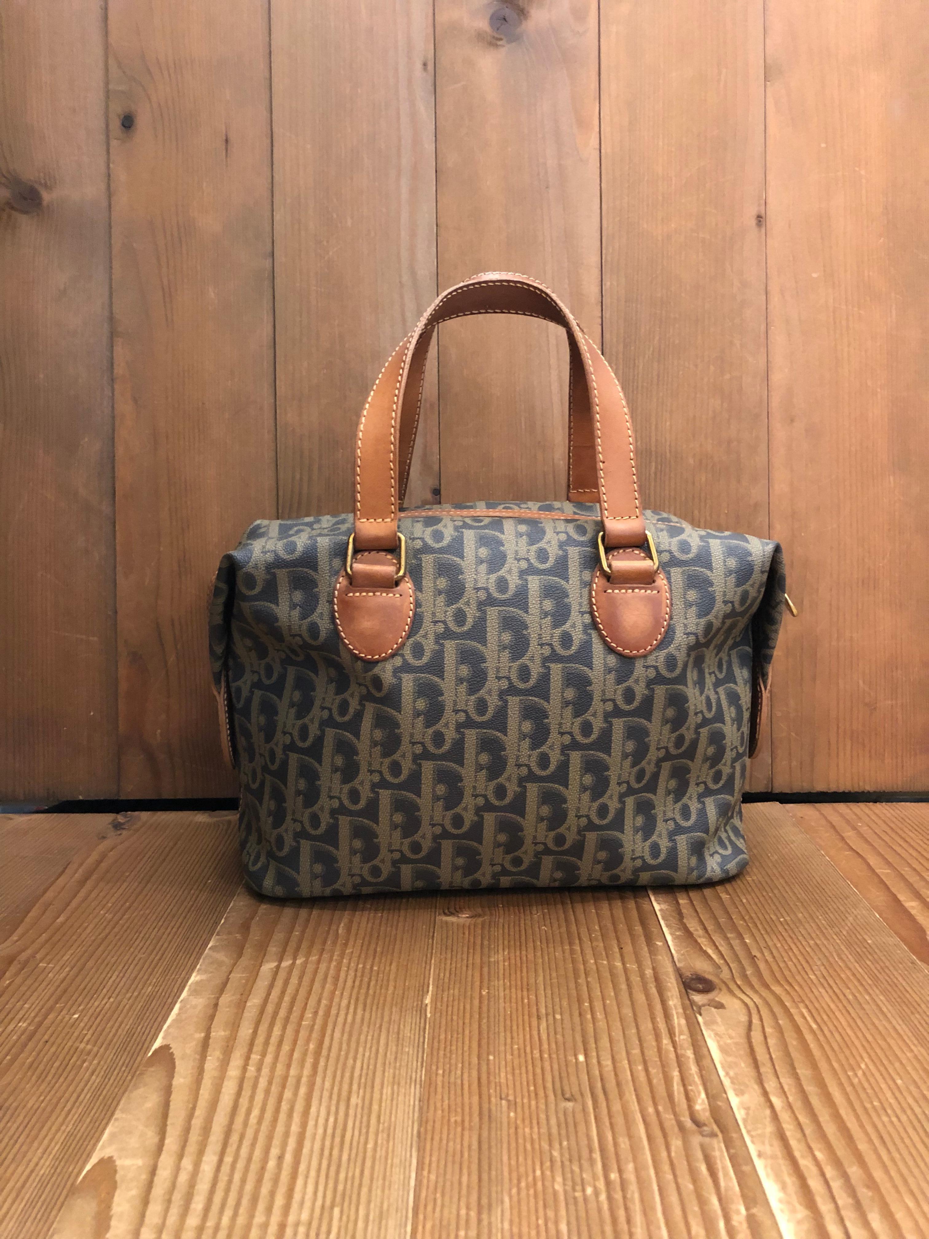 This vintage Christian Dior small boston bag is crafted of CD's coated trotter canvas in grey/khaki and cowhide leather featuring gold toned brass hardware. Top zipper closure opens to a black fabric interior featuring a zippered pocket. Snap
