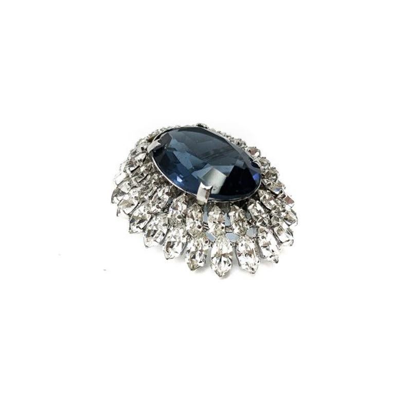 Just exquisite workmanship from Dior. This Vintage Christian Dior 1967 Crystal Brooch is nothing short of adorable. With it's glinting fancy cut tiered crystal surround to the large pool like deep blue central crystal. Set in rhodium plated metal