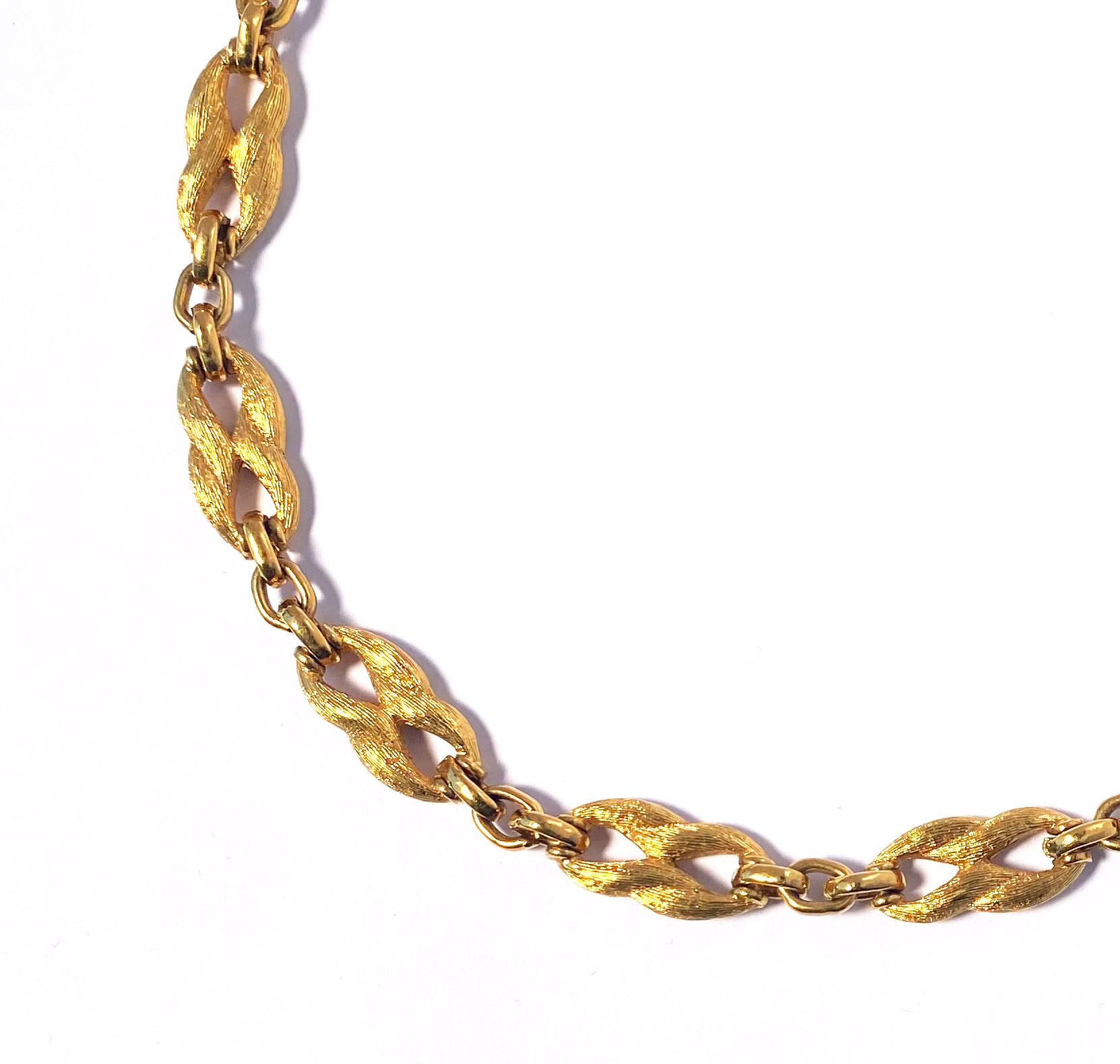 Vintage 1960s Christian Dior choker-length chain necklace in gold plate.  This necklace features elegant figure-8-shaped links with a unique wave-patterned lined texture, giving them a lustrous semi-matte finish.  The textured links alternate with