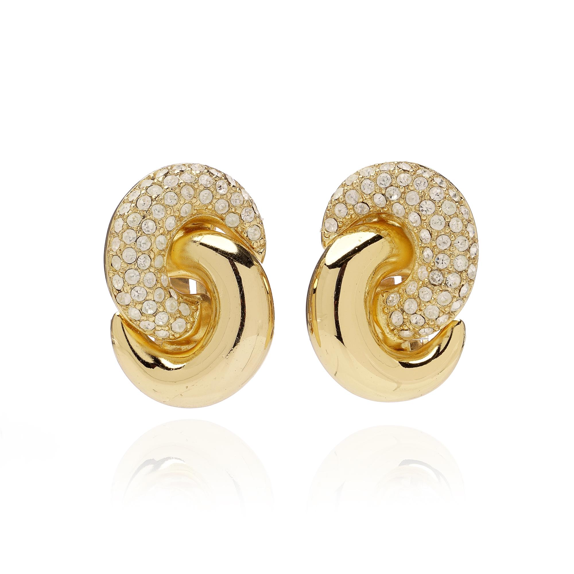 A pair of elegant vintage Christian Dior clip-on earrings, crafted in polished gold-tone metal and enhanced with sparkling crystal pavé. Designed in a sculptural swirl motif, these earrings capture the refined glamour of Dior’s vintage costume