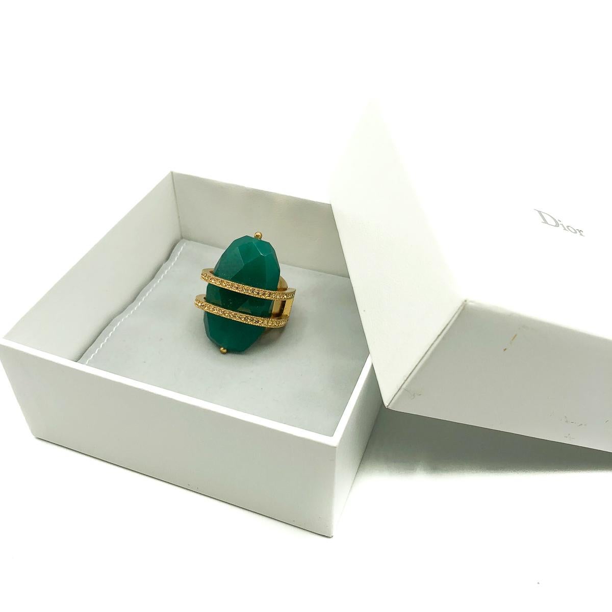 A Vintage Dior Cocktail Ring. Featuring a huge faceted green stock, almost rock like in it's proportions. Suspended by a crystal embellished double ring that circles around the stone to meet the wonderfully broad style shank. In gold plated metal.