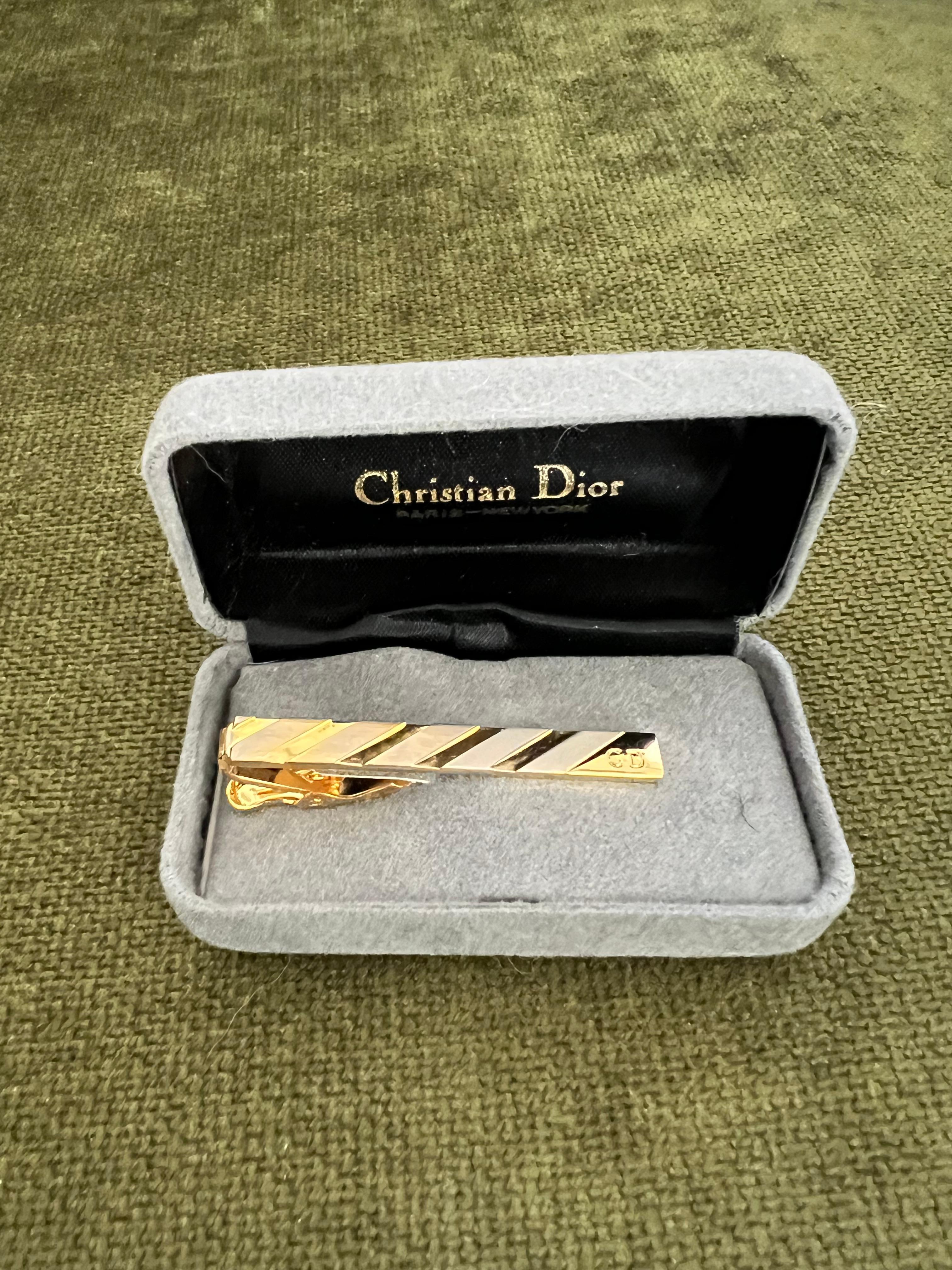 Vintage Christian Dior Gold Plate Tie Clip 
Circa 1970 In Original Case 
Featuring a front Dior logo, a textured ground.
“Circa 1990”
Original Gray Velvet with Black Satin Case 
In fantastic vintage condition
Retro, Chic, Art Deco and Classic
*